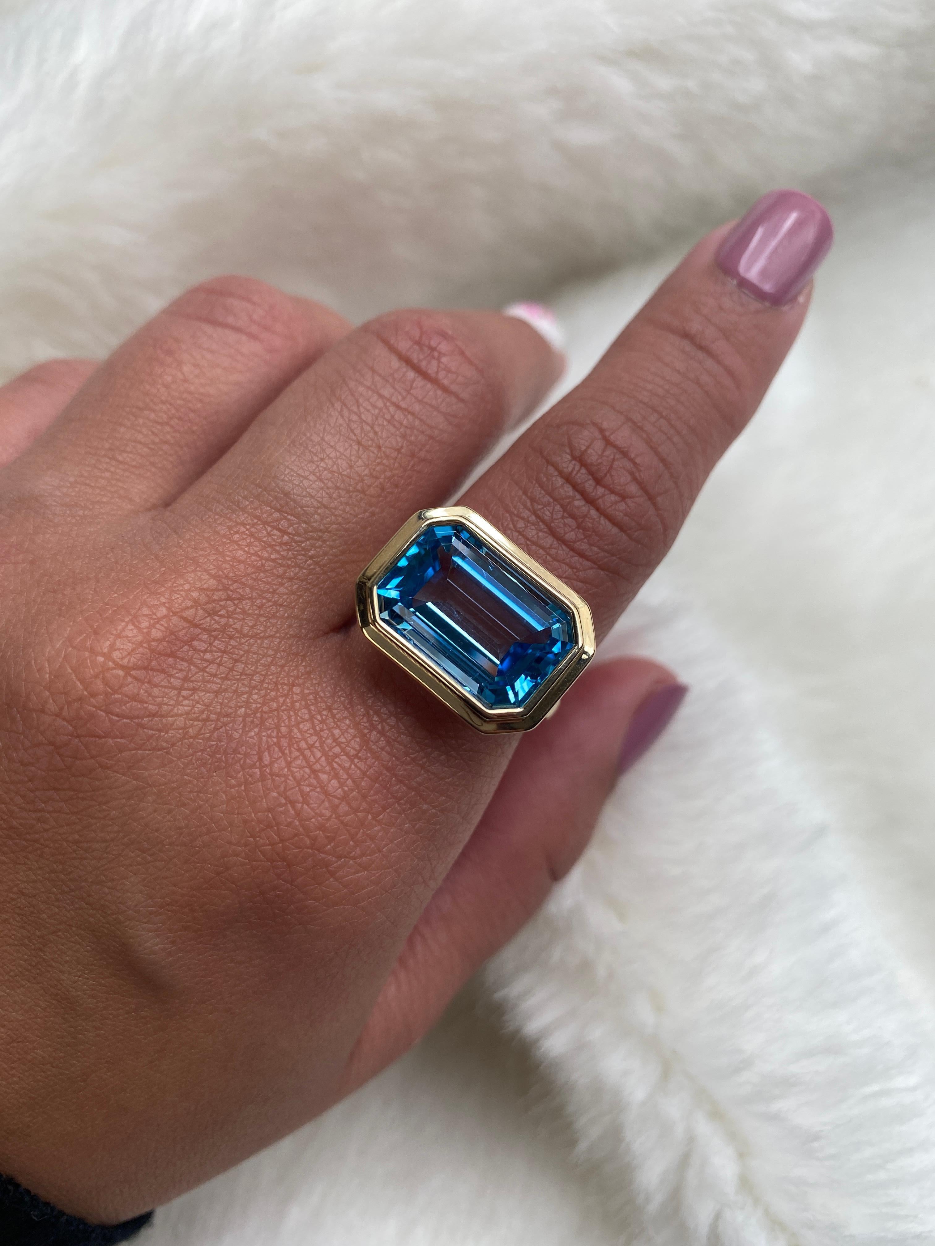 East-West Blue Topaz Emerald Cut Bezel Set Ring in 18K Yellow Gold, from 'Manhattan' Collection.  Minimalist lines yet bold structures is what our Manhattan Collection is all about. Our pieces represent the famous skyline and cityscapes of New York