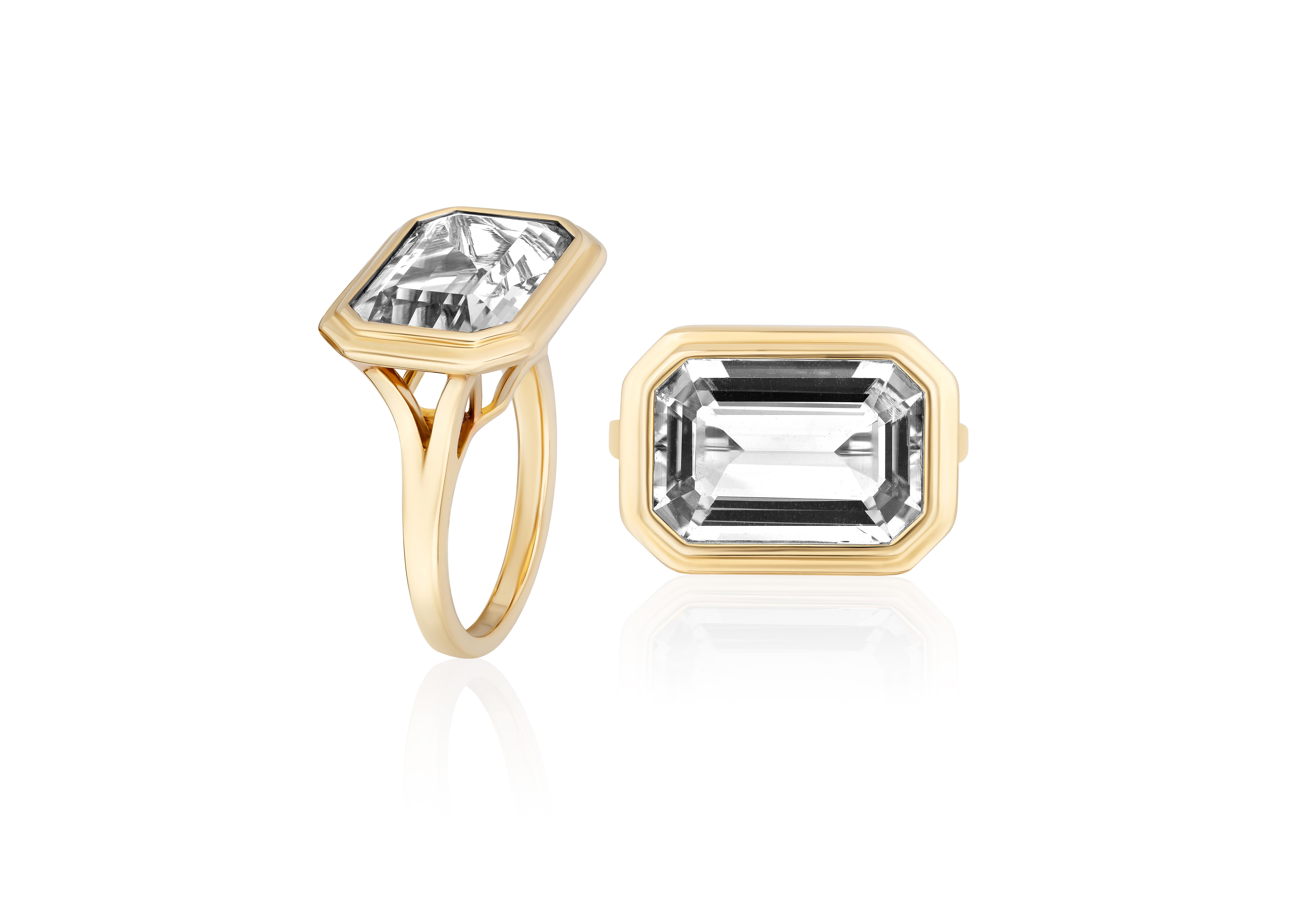 This East-West Rock Crystal Emerald Cut Bezel Set Ring in 18K Yellow Gold is a stunning piece from the 'Manhattan' Collection. Combining elegance with modernity, this ring showcases an emerald-cut rock crystal stone set in a bezel of lustrous 18K