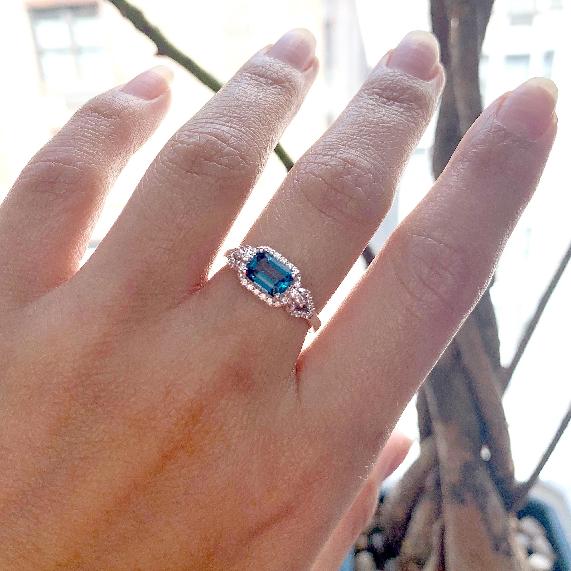 This London Blue Topaz Emerald Cut Ring from the 'Gossip' Collection is an elegant and sophisticated piece of jewelry. The central stone is a stunning emerald-cut London Blue Topaz, which is a rich shade of deep blue. The topaz is set in 18k white