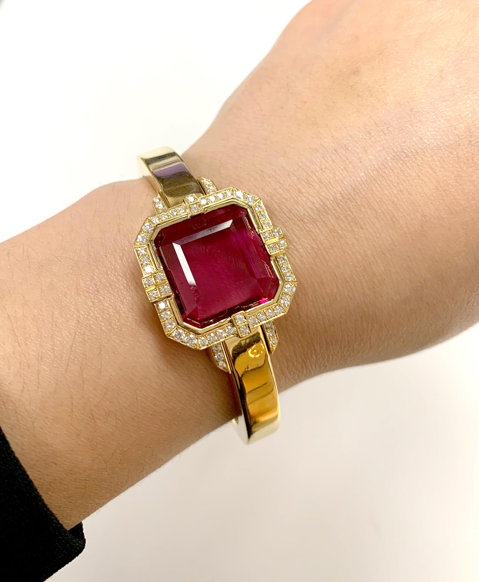 This Rubelite Emerald Cut Cuff with Diamonds in 18K Yellow Gold is a stunning piece of jewelry from the 'G-One' Collection. This cuff bracelet features a large, square emerald-cut Rubelite gemstone set in 18K yellow gold, surrounded by a halo of