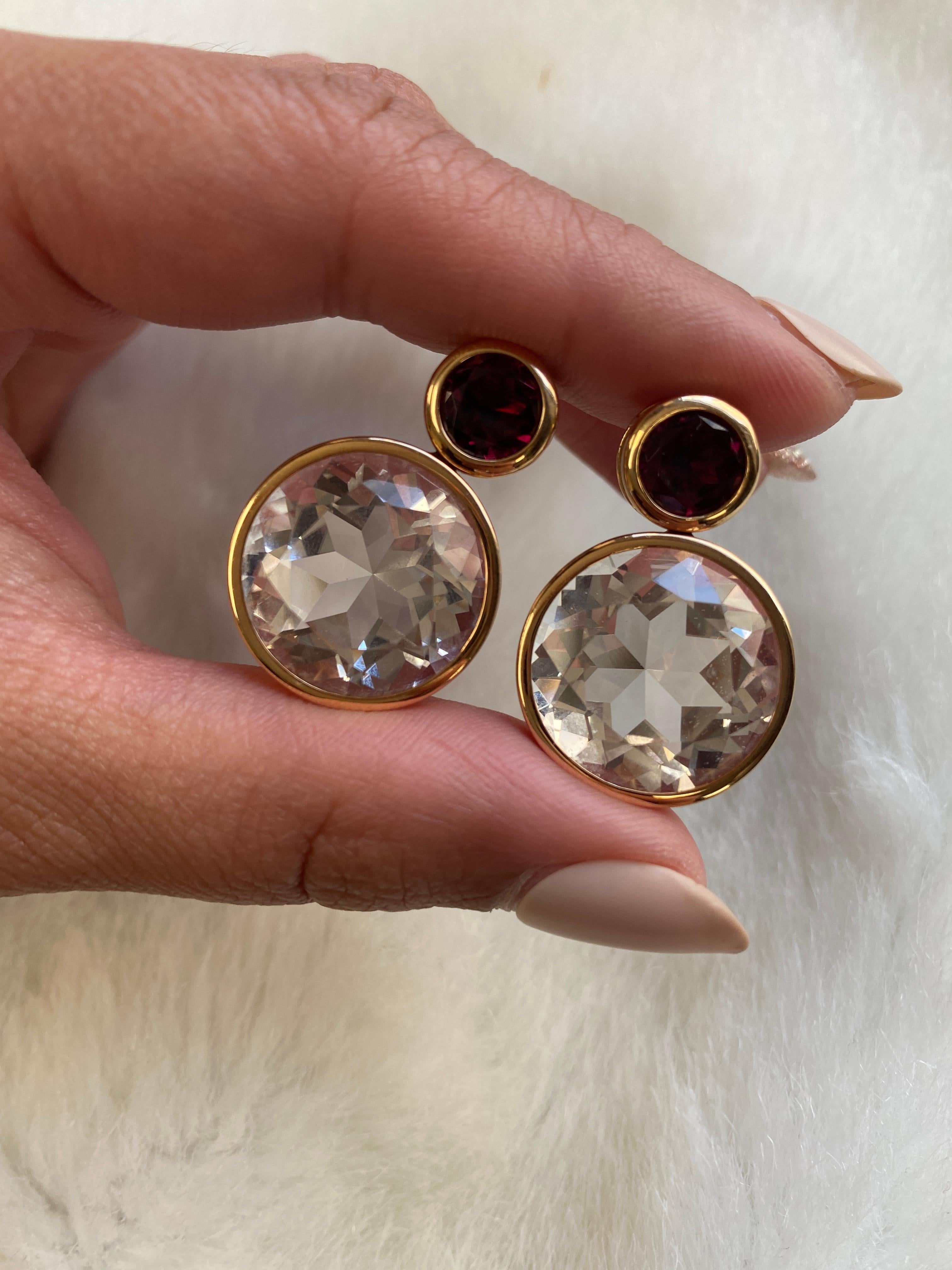 These Faceted Rock Crystal & Garnet Earrings from the 'Gossip' Collection are a stunning pair of earrings made from 18K rose gold. The earrings feature faceted rock crystal stones that shimmer in the light, along with garnet gemstones that add a