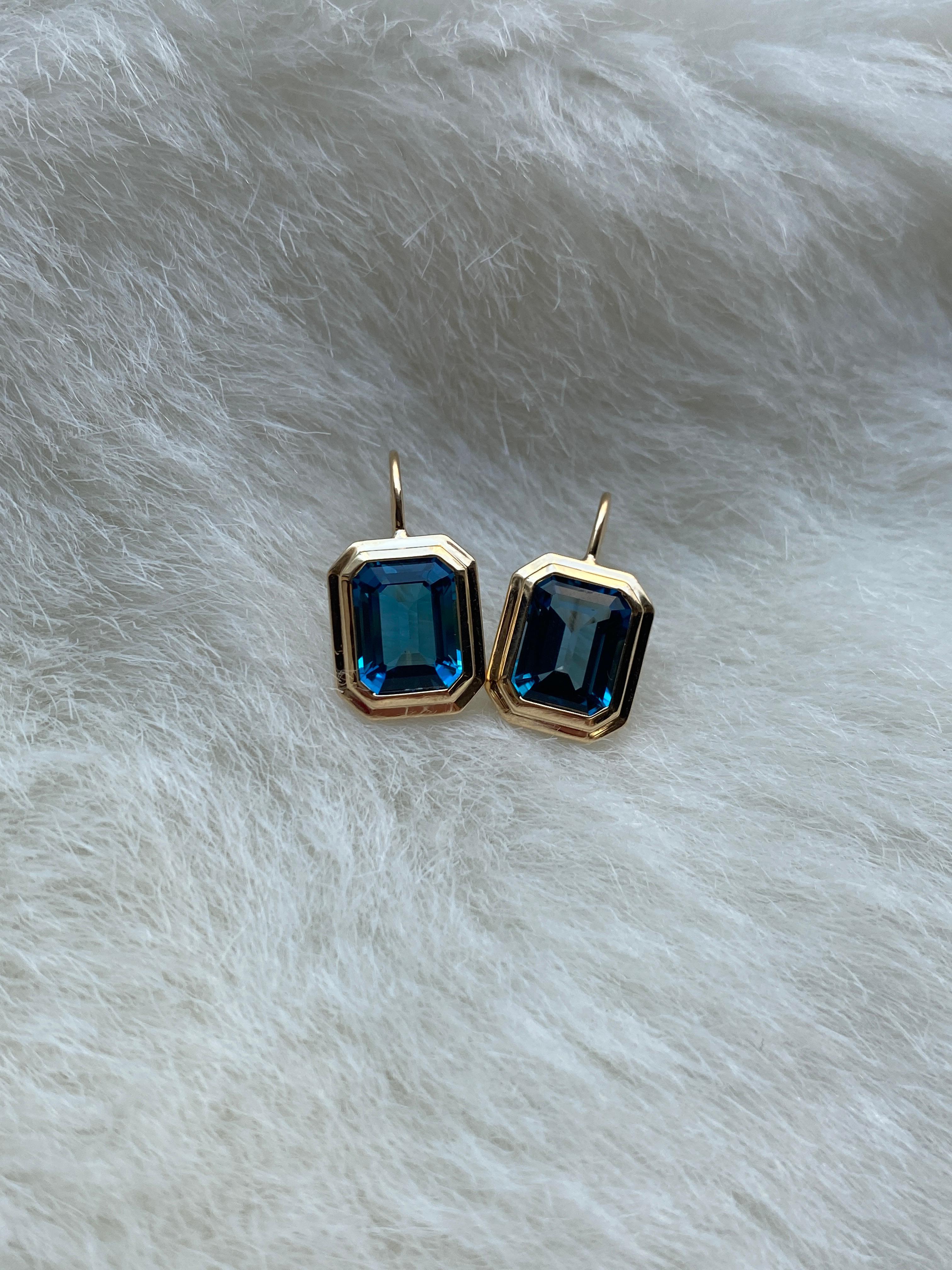 These London Blue Topaz Emerald Cut Bezel Set Earrings on Wire in 18K Yellow Gold from the 'Manhattan Collection are a stunning and sophisticated jewelry piece. These earrings feature exquisite london blue topaz gemstones with an elegant emerald