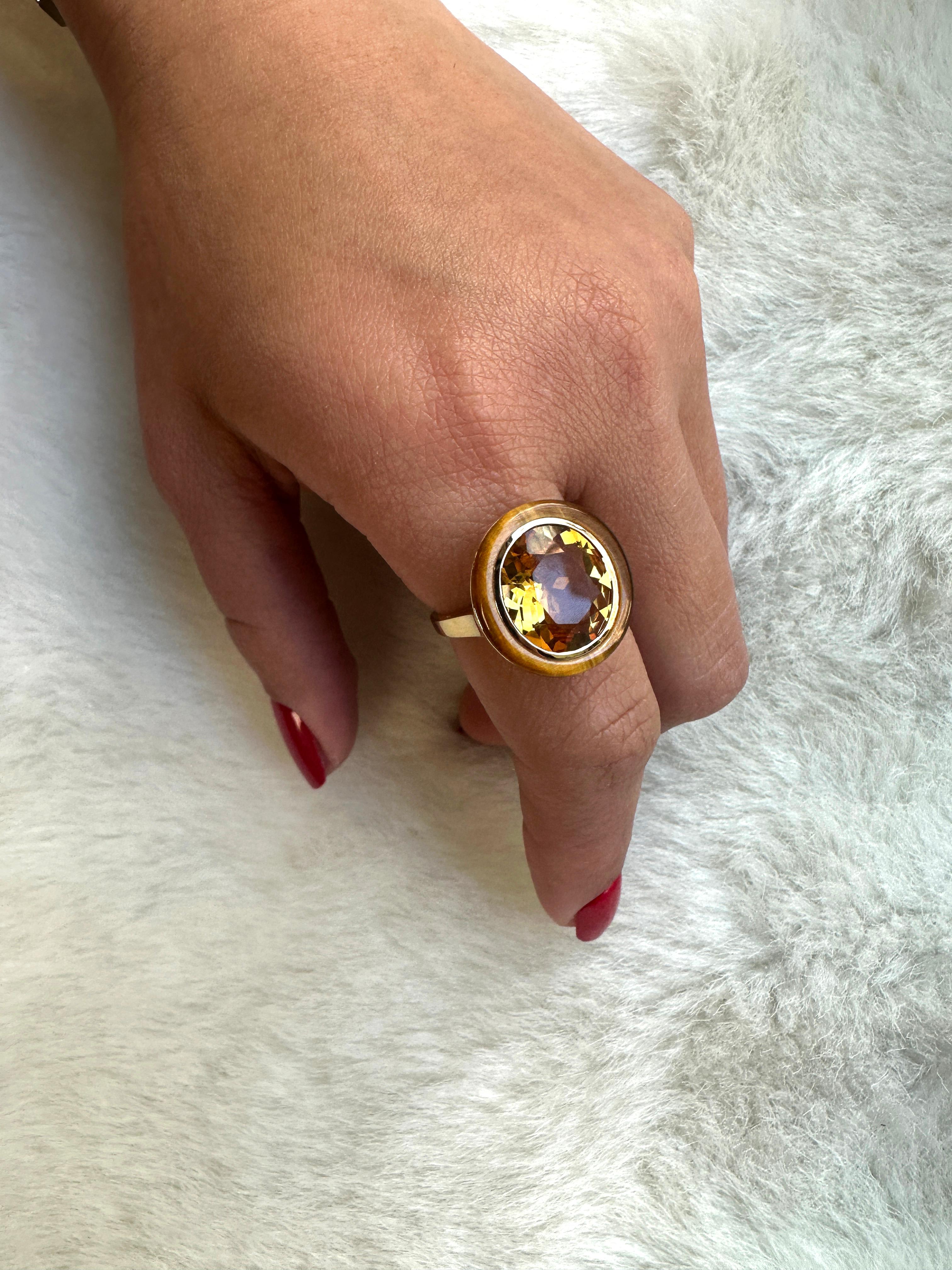 This Orange Citrine & Tiger's Eye Oval Ring in 18K Yellow Gold from the 'Melange' Collection is a stunning piece of jewelry that is perfect for those who love unique and bold designs. The ring features an oval-shaped orange citrine stone and tiger's