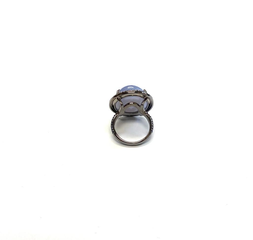This Blue Chalcedony Cabochon Ring with Diamonds and Blue Sapphire is a stunning piece of jewelry from the 'Limited Edition' Collection. Crafted from 18k white gold and accented with light black rhodium, the ring features a cabochon cut blue