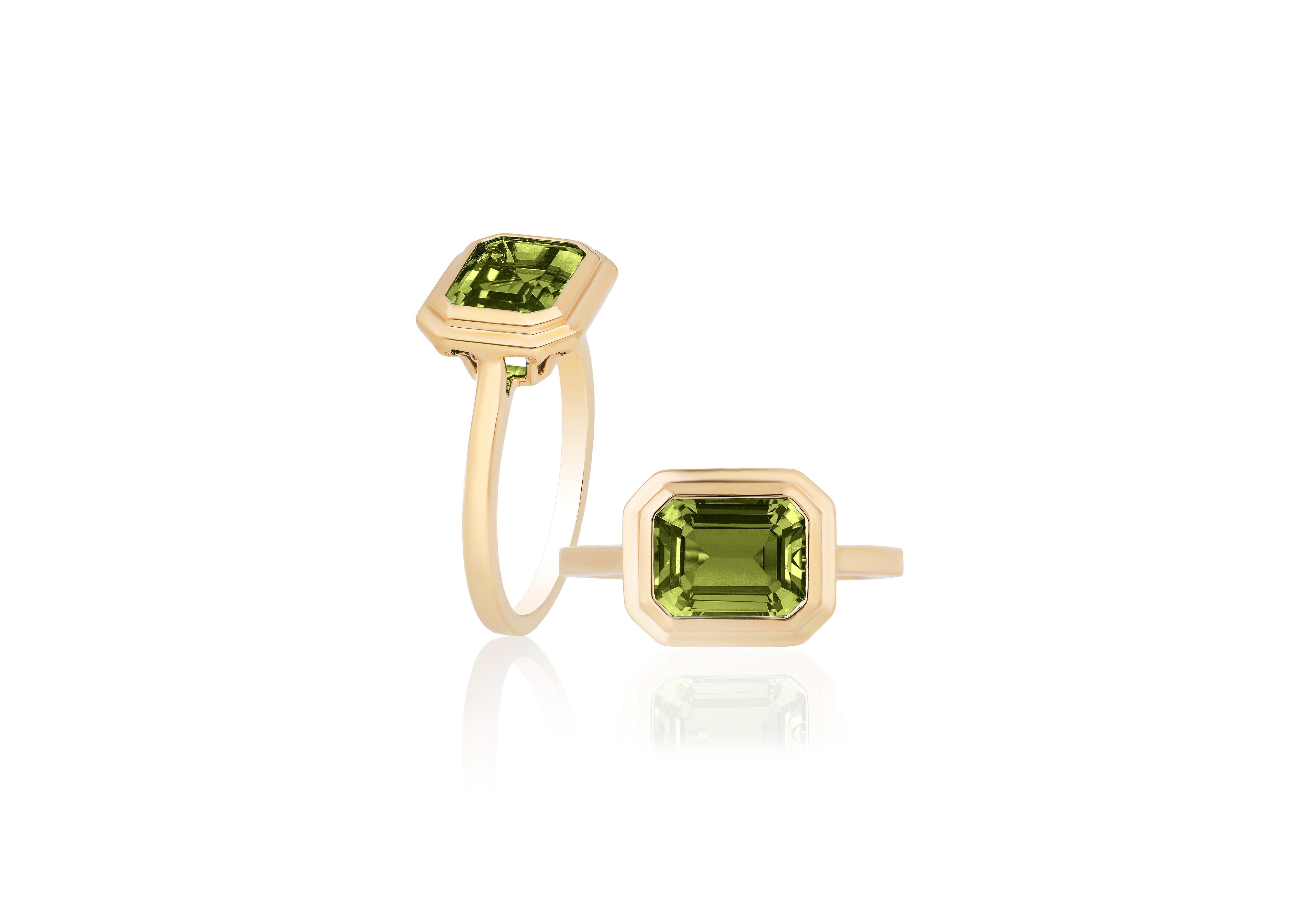 This Peridot Emerald Cut Bezel Set Ring in 18K Yellow Gold is a sleek piece from the 'Manhattan' Collection. It features a stunning emerald-cut Peridot stone set in a 18K yellow gold bezel. This ring embodies modern elegance, offering a touch of