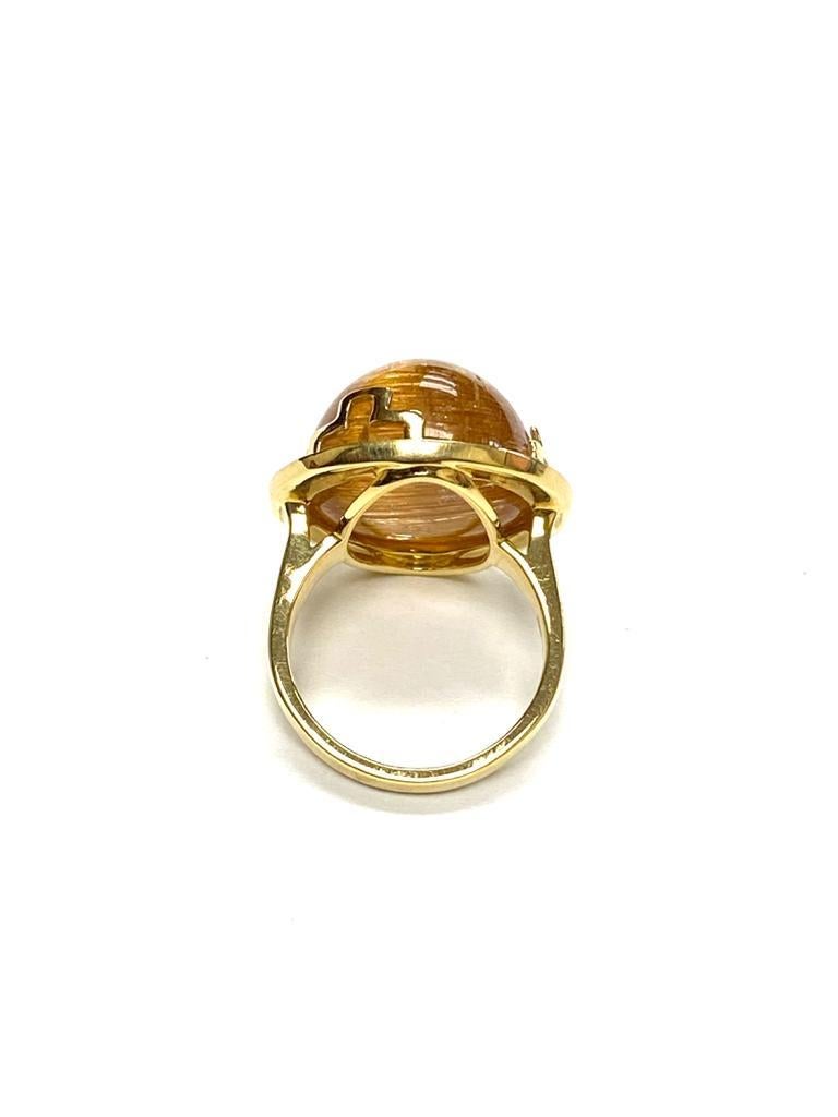 This Large Round Rutilated Ring with Diamonds is a stunning piece of jewelry from the 'Rock N Roll' Collection. The ring features a large, round rutilated quartz stone, with delicate golden threads of rutile running through it. The stone is set in
