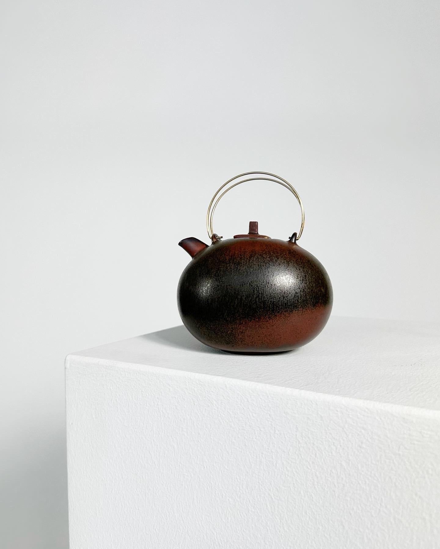 Rare small teapot by Gösta Grähs for Rörstrand factory in Sweden, 1980s. 

Hand-made stoneware with a beautiful mossy brown and rusty red glaze, finished with delicate brass handles. 

Excellent condition, marked and signed underneath.

Height: 14