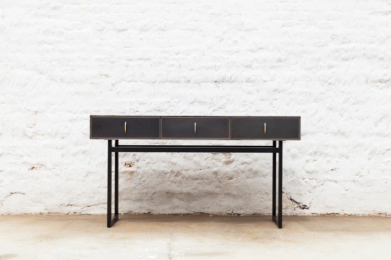 The harmonious mix of materials enhances the beauty of this Gotham console. The console features rich oxidized Ambrosia maple wood, a blackened steel frame, three blackened bronze encased in epoxy resin drawers with black leather lining and