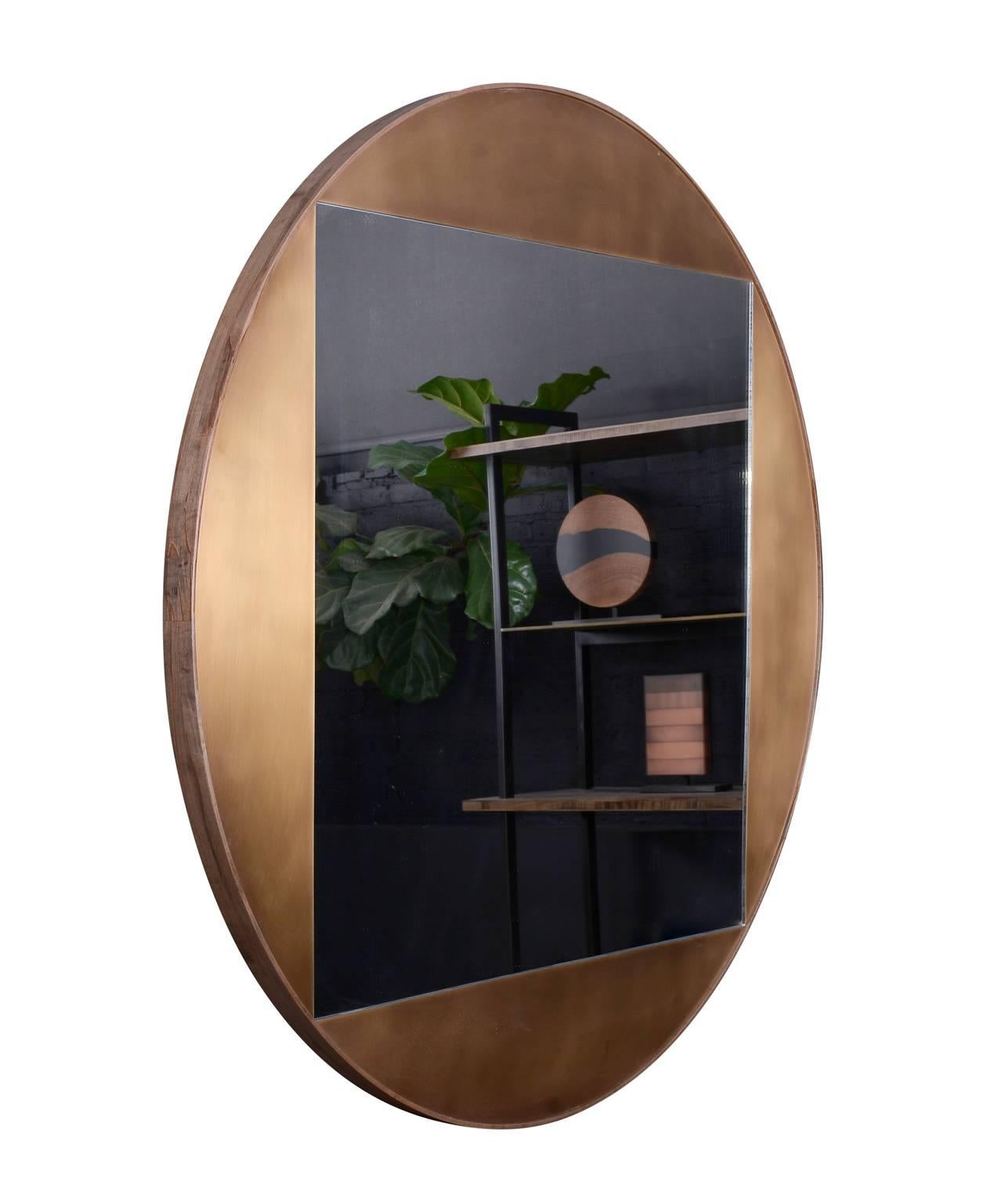 Part of the elegant Gotham collection, the round mirror is composed of patinated bronze and oxidized ambrosia maple. The juxtaposition of shapes, both sharp and curved, lends balance and sophistication to this piece. Regular lead time 10-12