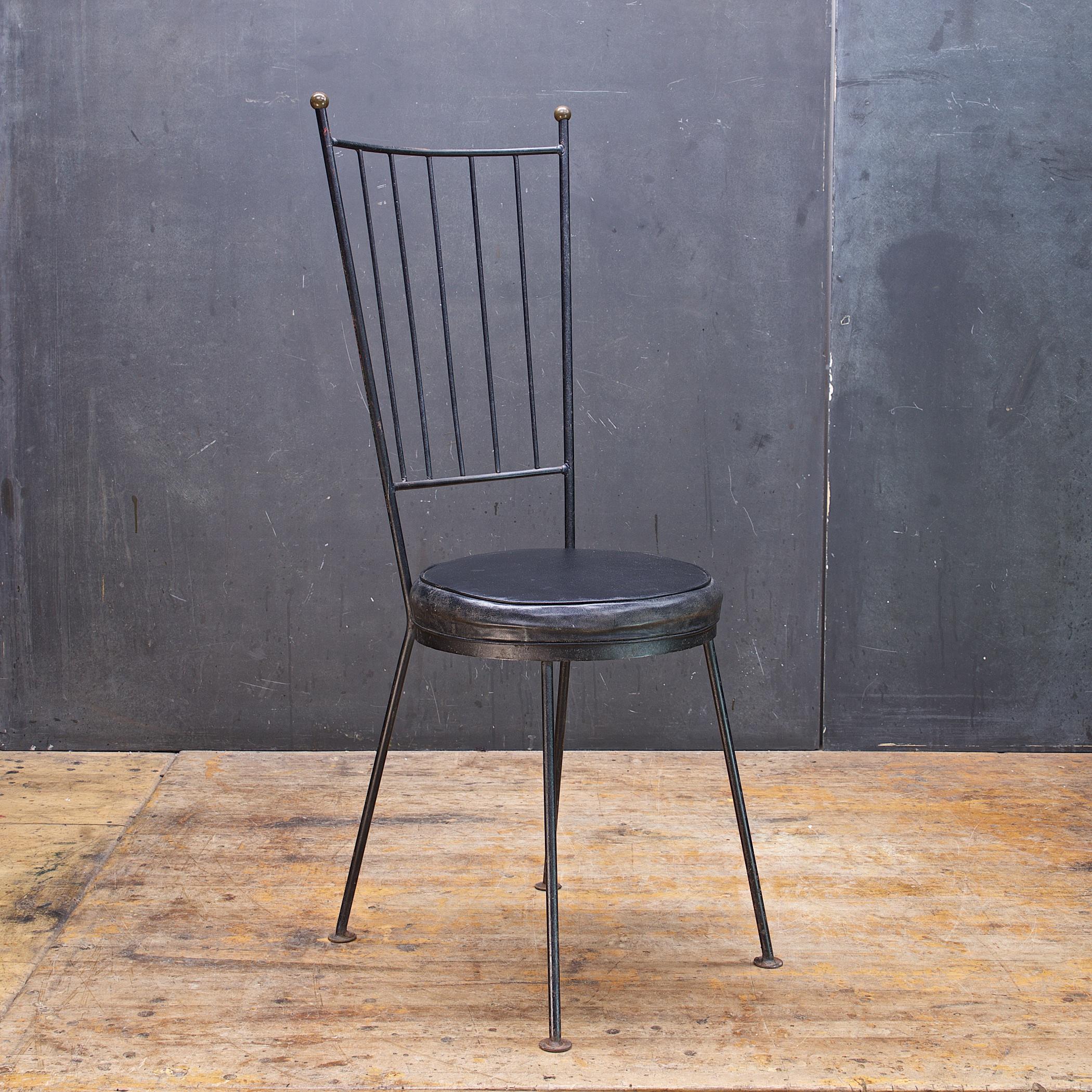 Very fun, low cost 50s minimally constructed tall enameled steel rod dining chair. This example has aged nicely, tarnished brass finials, and even the black naugahyde has taken on a grayish patina.
