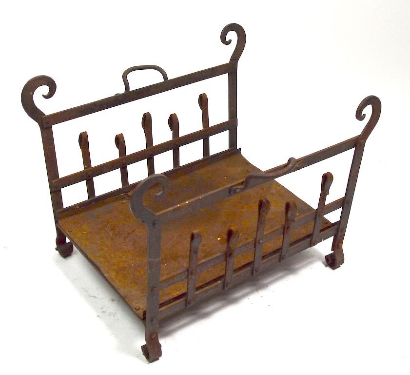 Arts & Crafts Mission wrought iron log holder in rust surface finish. Structurally sturdy and free of breaks or repairs, metal tray base has a slight dent at outer edge, as shown - inconsequential and does not effect function.