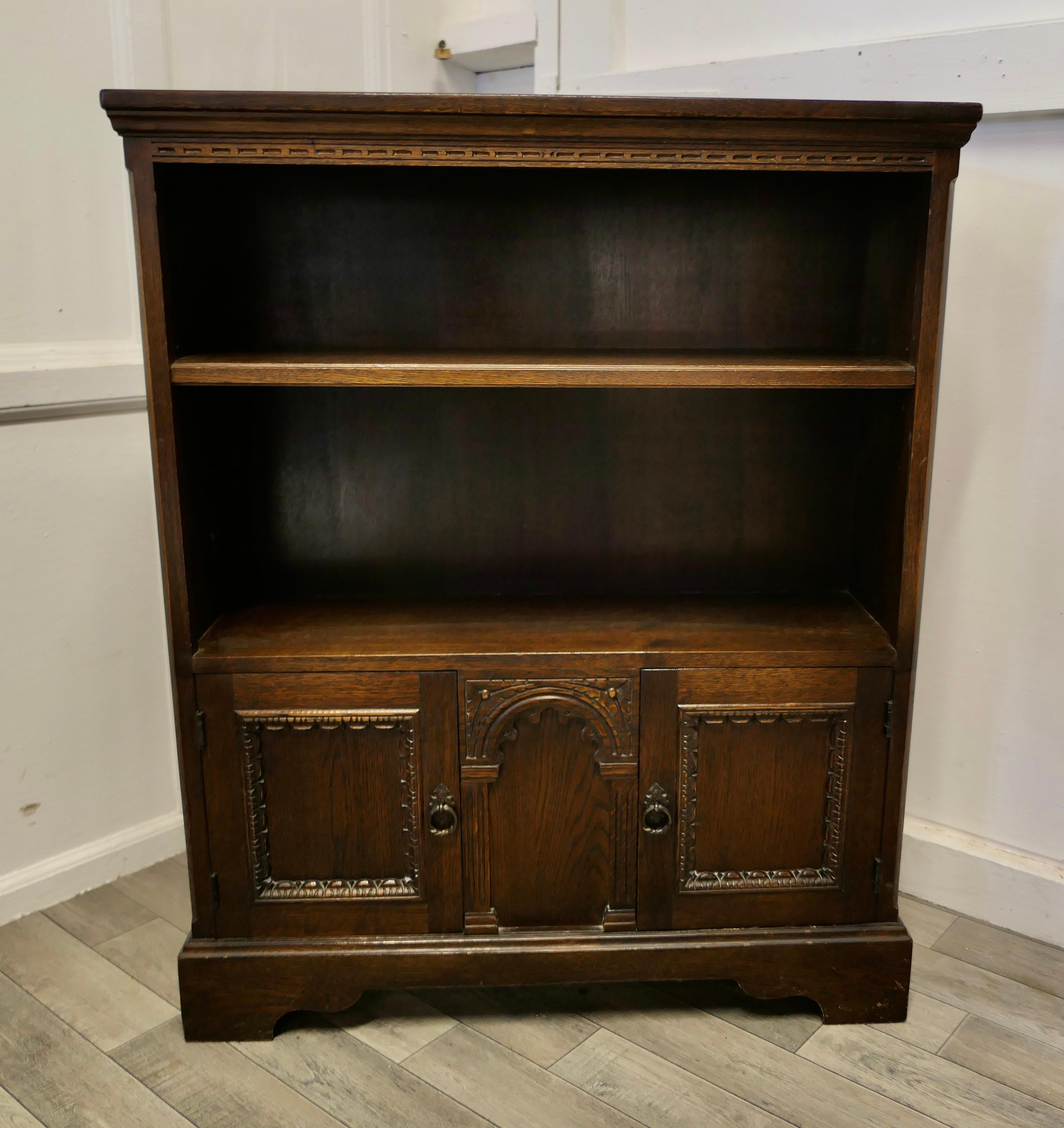Gothic Carved Oak open bookcase with Cupboard by Old Charm

A Charming little piece dating from about 1920, the bookcase has an adjustable shelf and a long cupboard at the bottom with two doors and central panel
The Cupboard is made by Old Charm,