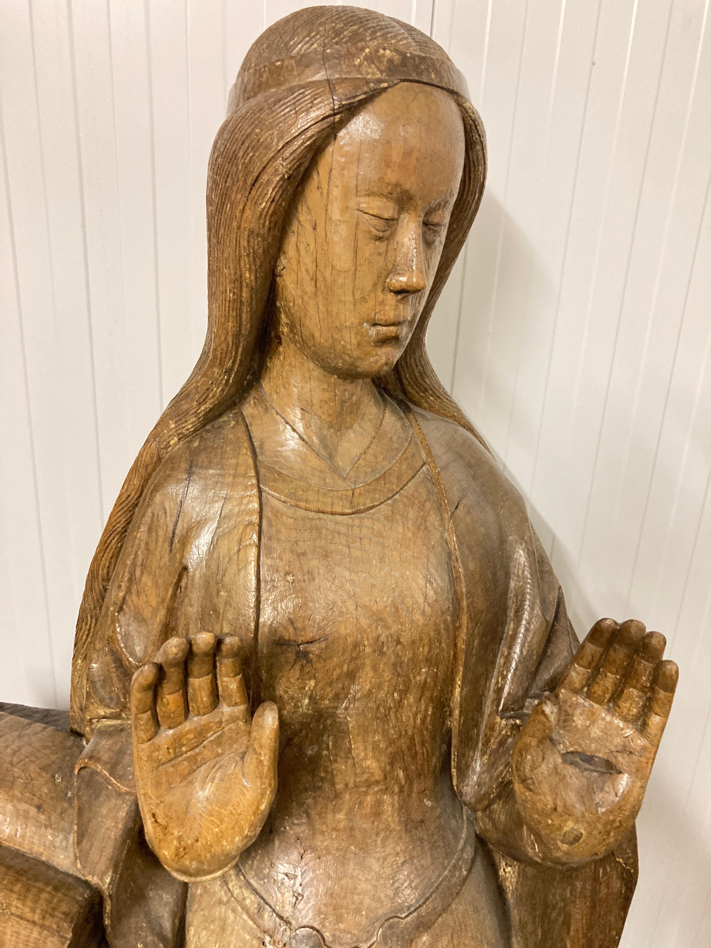 15th Century Oak Wood Sculpture of the Virgin of the Annunciation beside a lectern supporting an opened book, the Virgin with both hands upraised ( one repaired) turning slightly to the left, her demeanour redolent of strength, compassion and