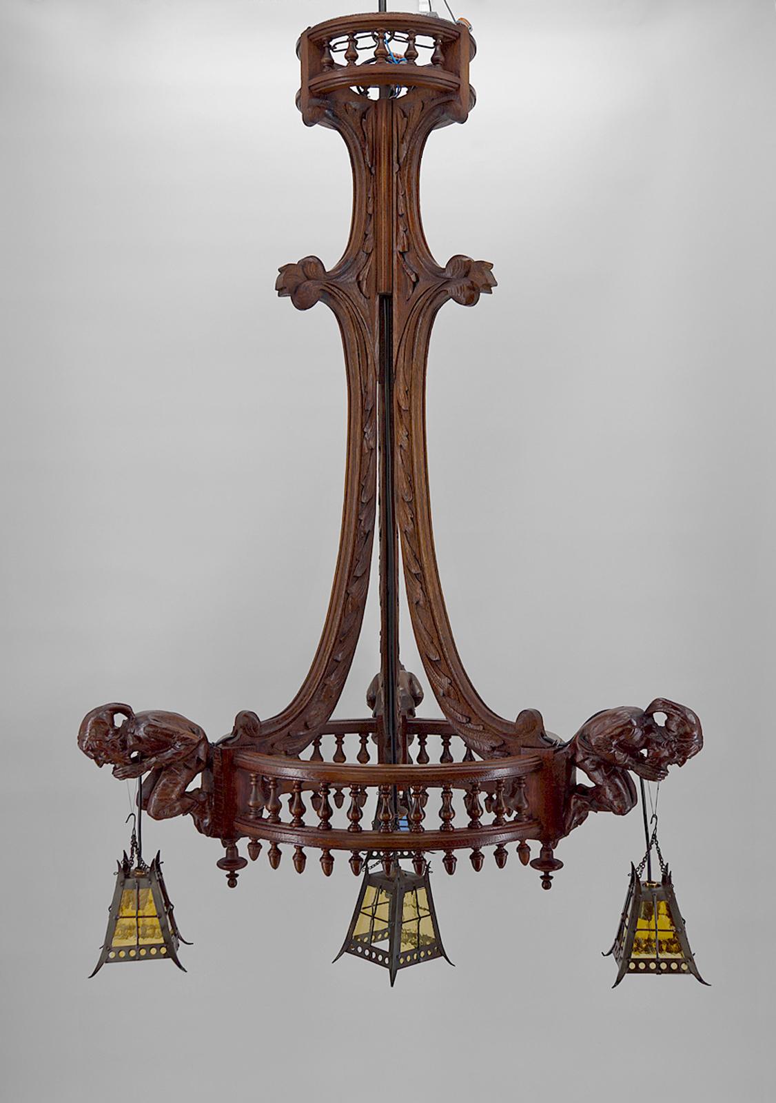 Imposing chandelier / suspension / pendant in oak, composed of 3 branches with at the end of each a jester / buffoon holding a lantern. The branches are joined by a turned wooden baluster.
The jesters are carved from basswood.
The lanterns are in