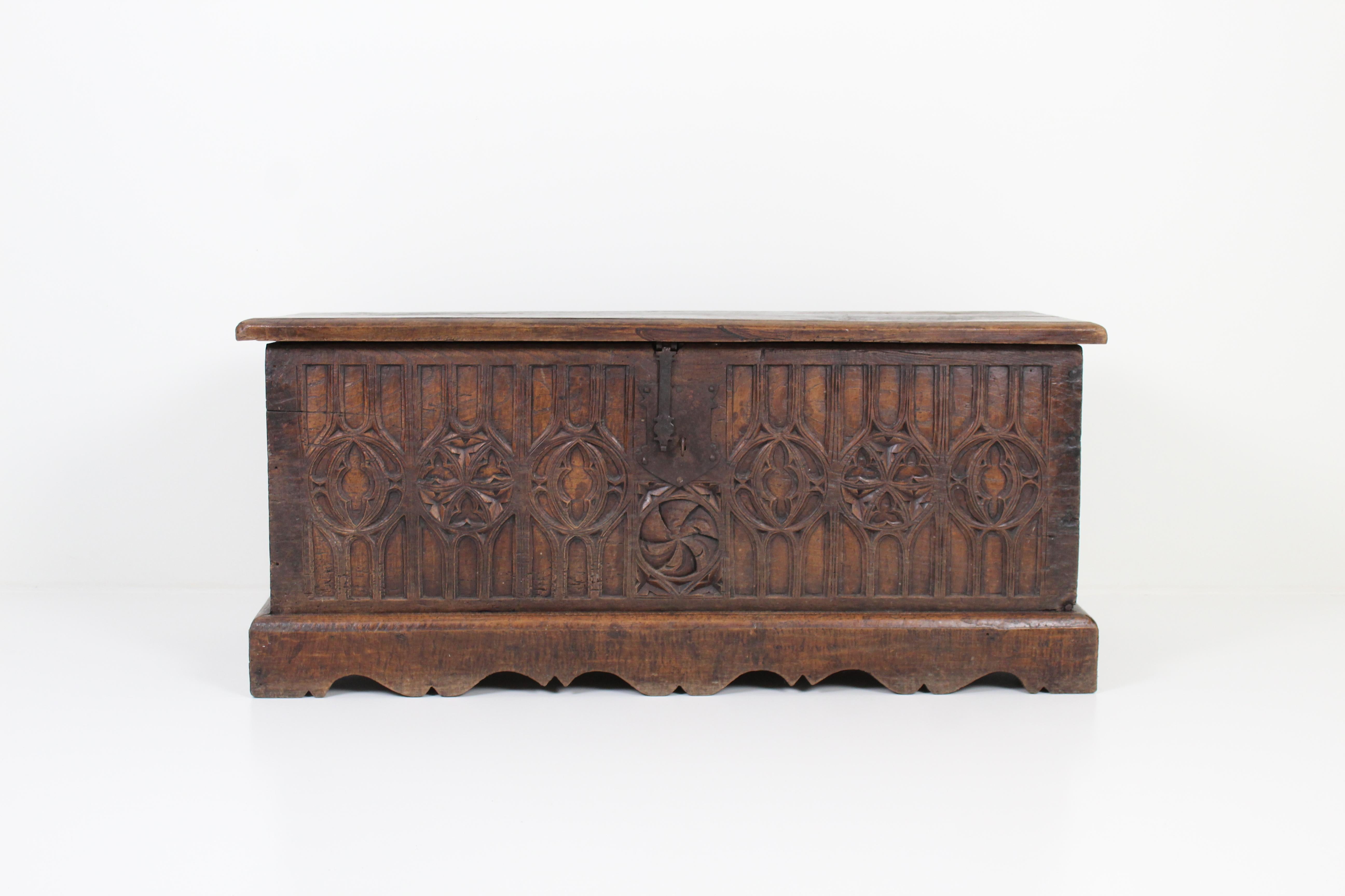 An antique Gothic French chest with a carved wood exterior and metal hardware. 