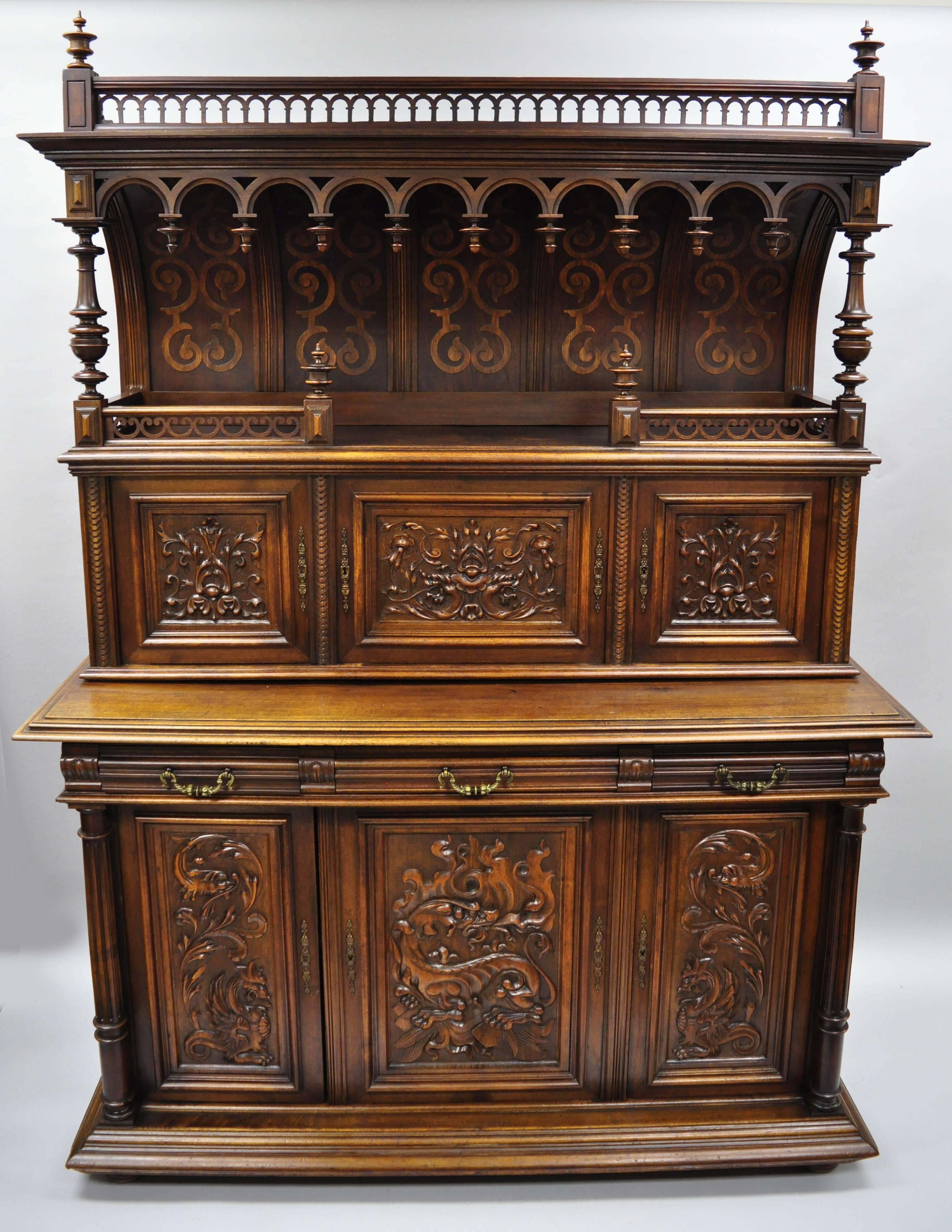 Antique 19th century Gothic Renaissance Revival figural carved walnut sideboard. This remarkable item features two-part construction with ornate carvings throughout including dragons/griffins and flame and acanthus leafy scroll work. Sideboard has