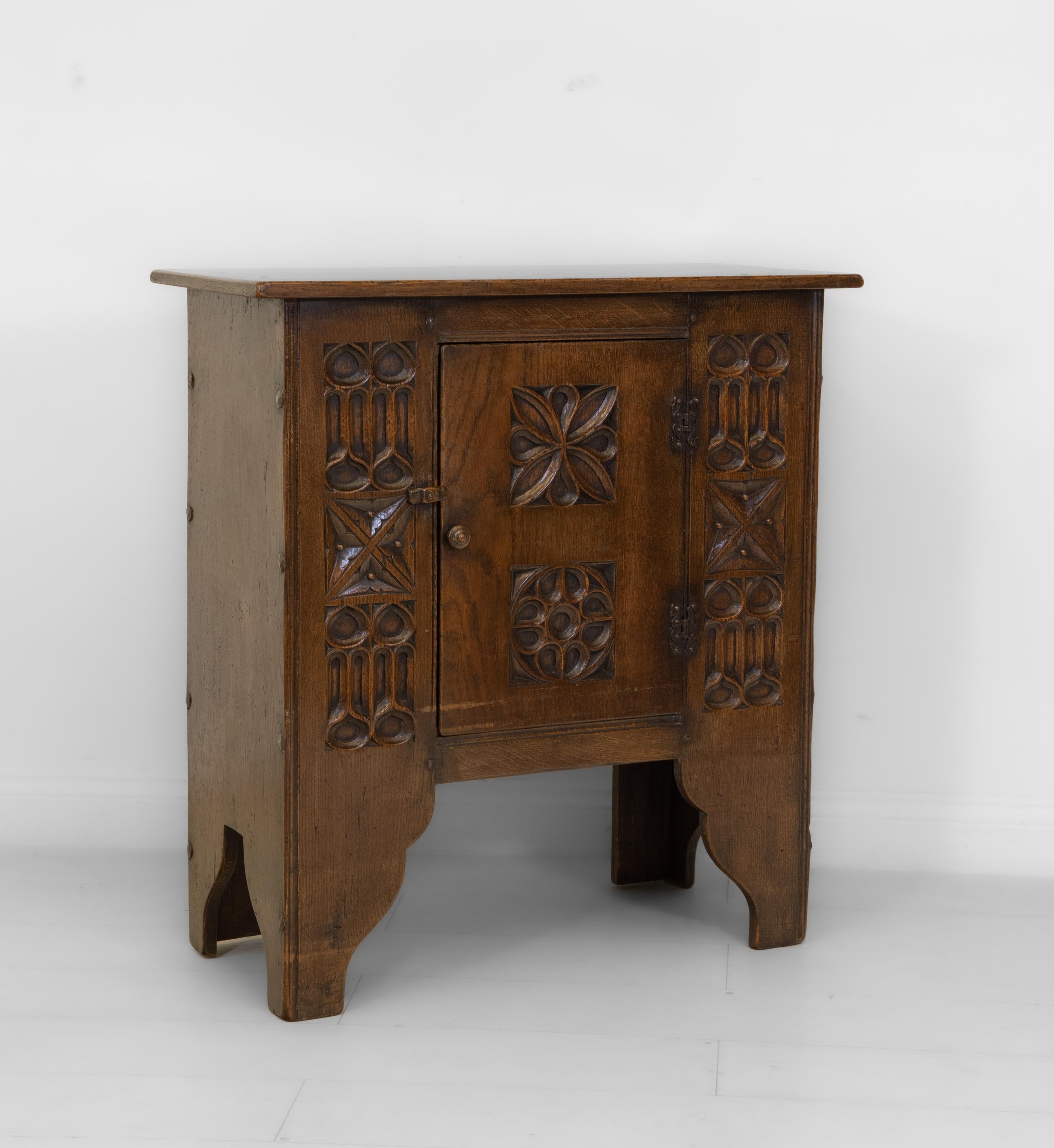 A Gothic Revival carved oak cabinet of nice proportions. Circa late 20th century. 

The cabinet having hand carved gothic tracery decoration to the front, and hand made metal studs to the sides. The whole cabinet has been given an aged appearance