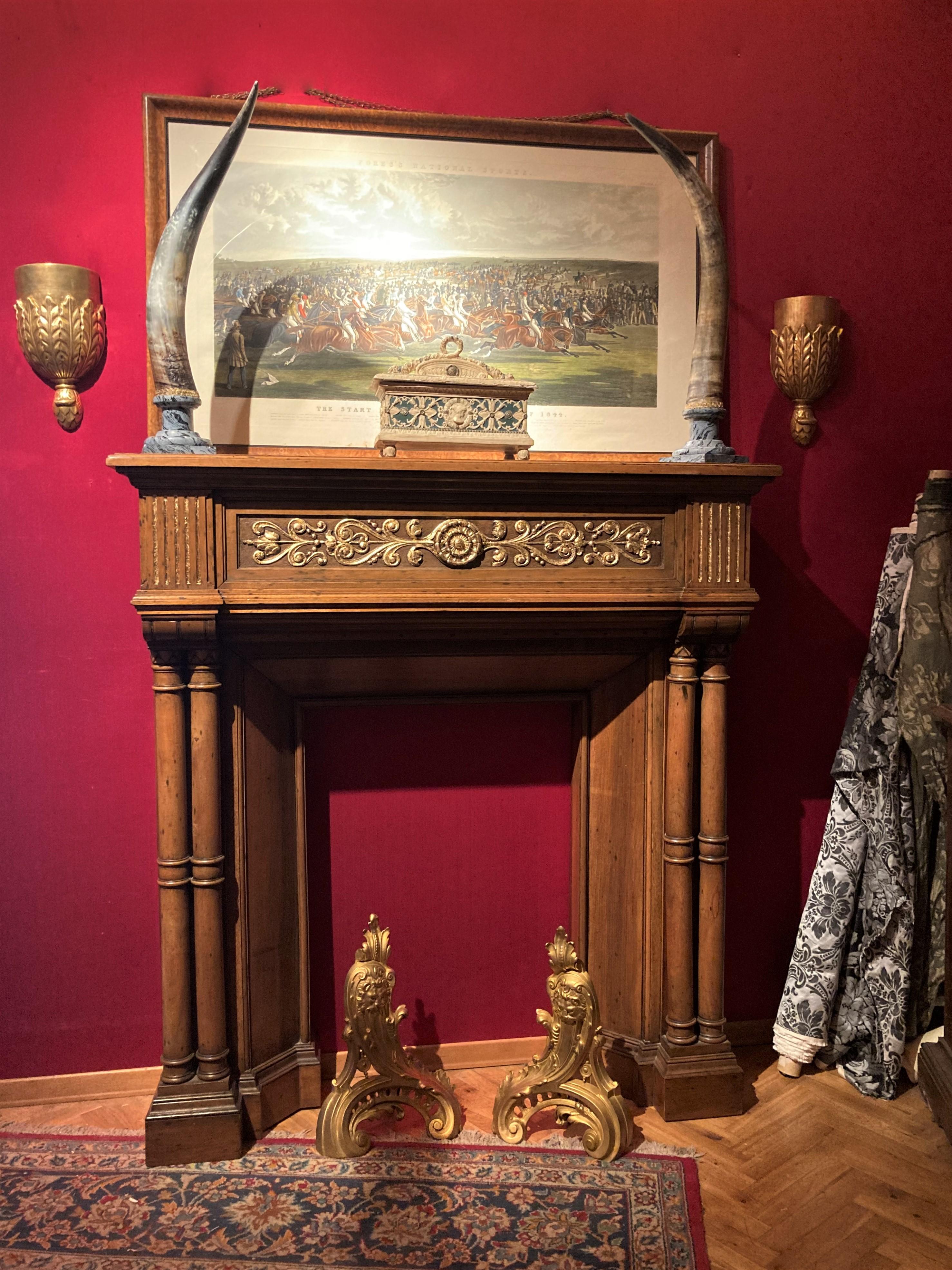 This Italian late 19th century quite large scale, impressive and profusely carved, solid parcel gilt walnut wood chimney piece in the neo-Gothic style features eye-pleasing architectural details including twin fluted columns sculpted in the round,