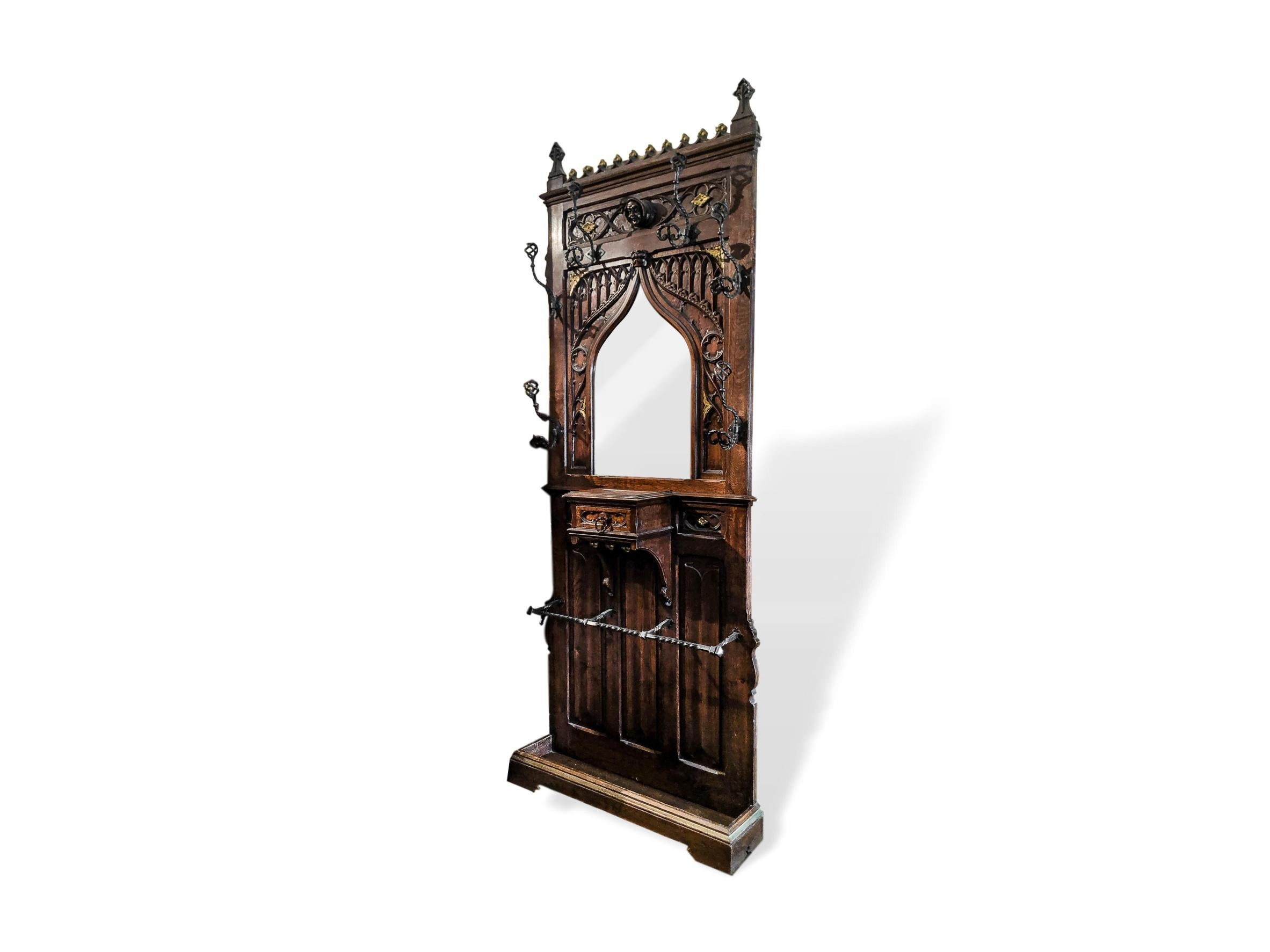 Gothic Revival coat rack hall tree umbrella stand hand carved mirror, French, circa 1880, with glove drawer below the beveled mirror, with blind Gothic tracery, and richly gilded highlights, with three beautifully hand carved linen fold panels on a