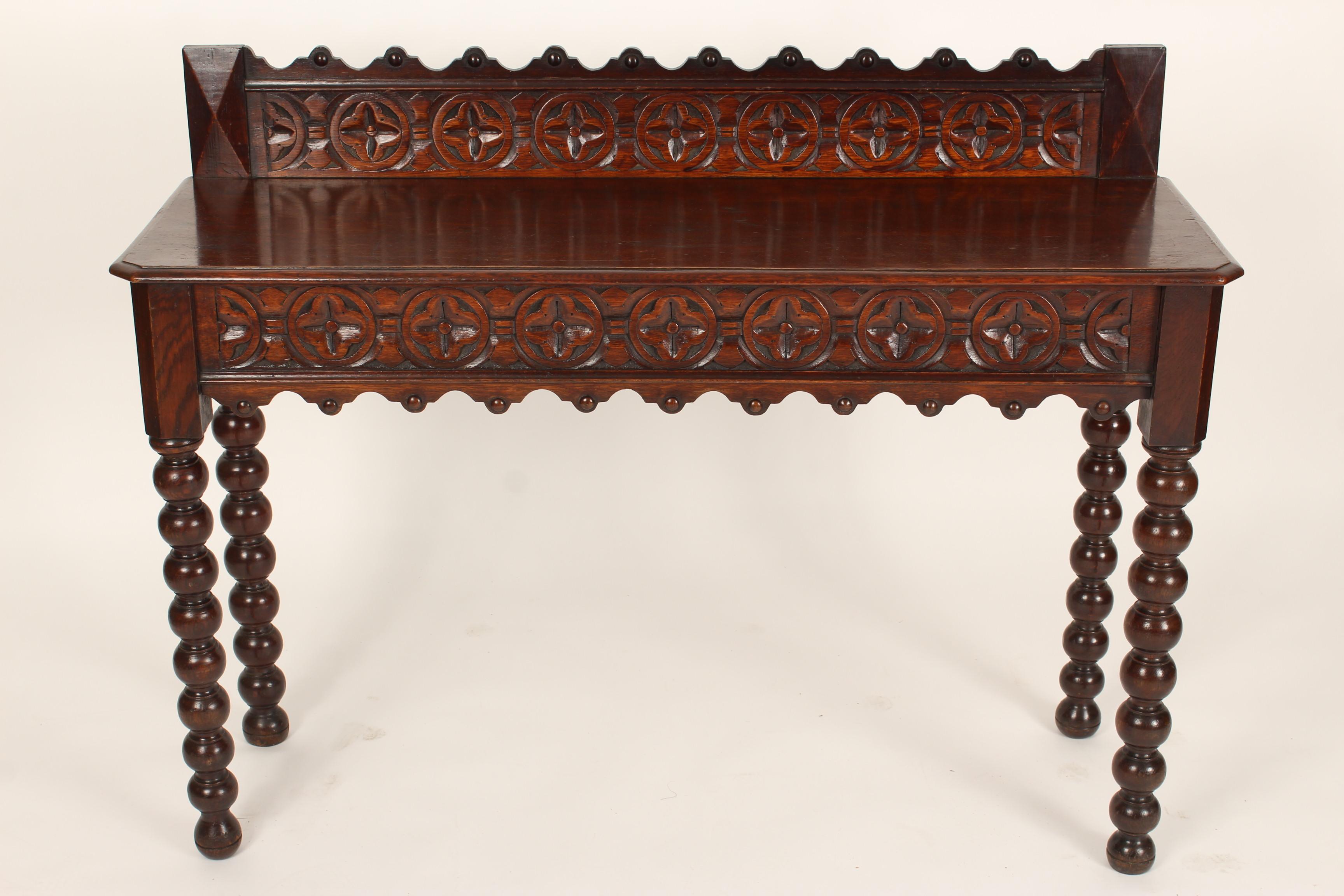 Gothic revival carved oak console table with bobbin turned legs, late 19th century. Height to top of back splash 36