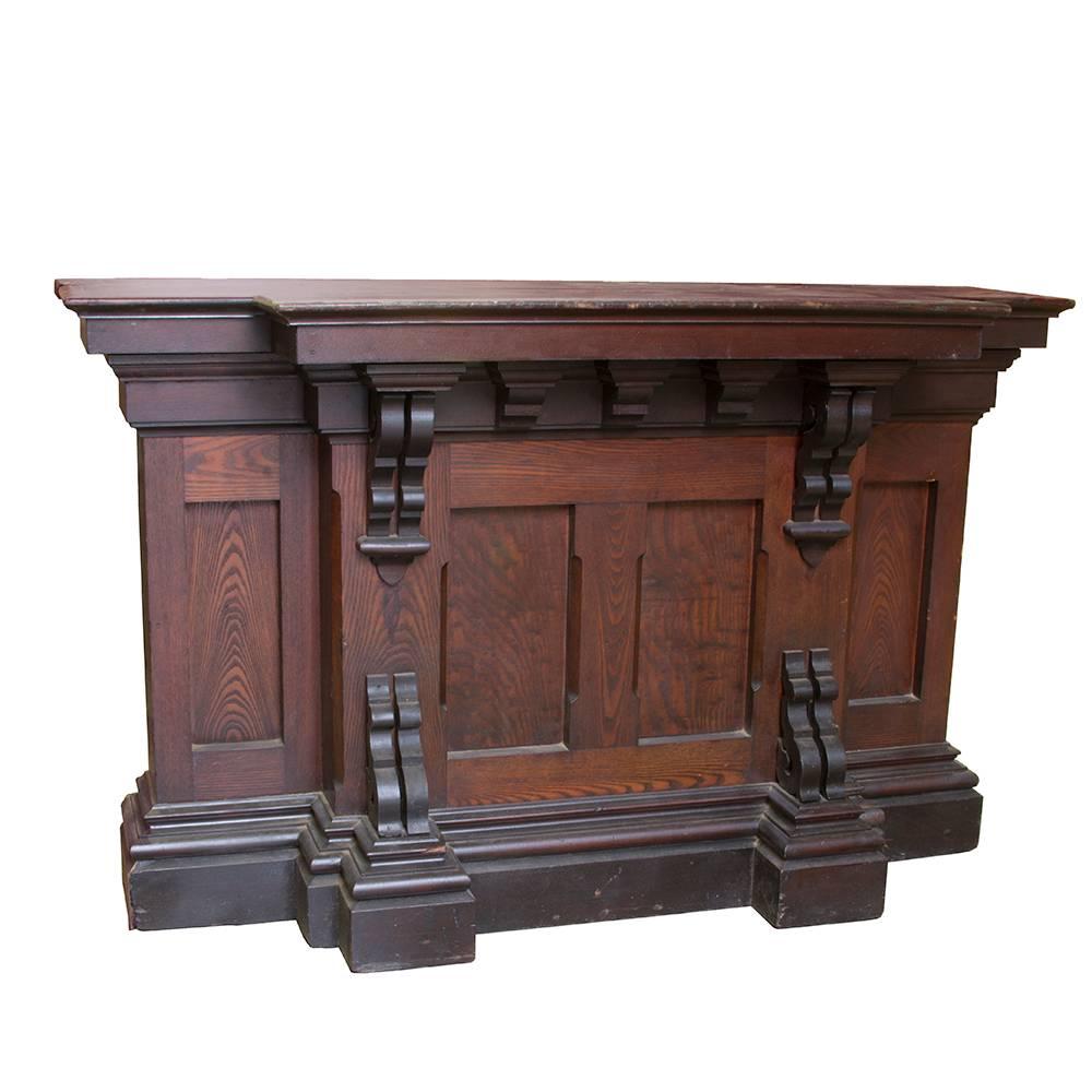 Dark and lovely, this petite counter could double as a reception desk or even a bar. The “T” shaped profile makes for a good gathering spot, and the recessed paneling and scrollwork corbels will draw them in every time. Solid Victorian style in
