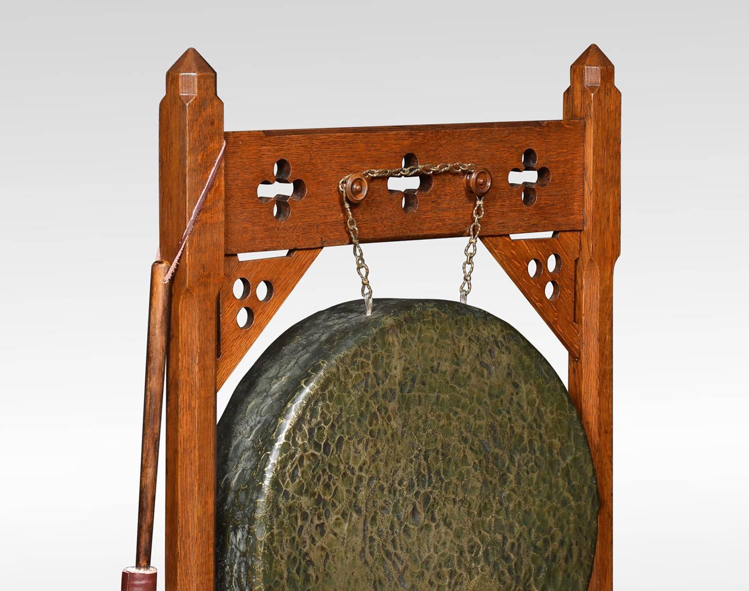 Gothic Revival late Victorian carved oak framed brass dinner gong and beater, the stand having canted corner supports with suspended brass gong to centre raised up on shaped feet.

Dimensions:
Height 41.5 inches
Width 24 inches
Depth 14.5