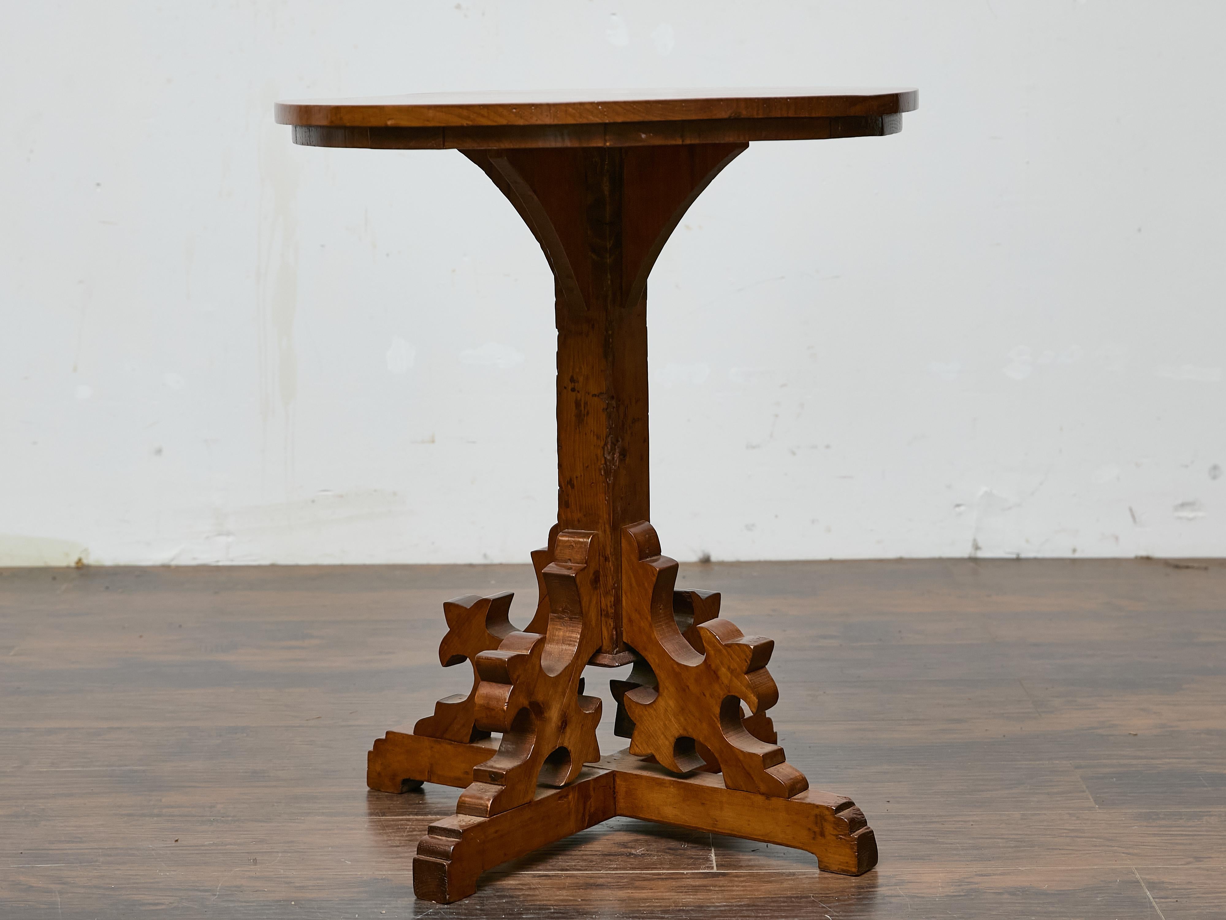 Avec sa base sculpturale et son grain de pin chaud, cette table d'appoint anglaise du XIXe siècle offre un mélange distinctif de caractère rustique et de charme néo-gothique. Le plateau circulaire est constitué de planches de pin massif aux nœuds