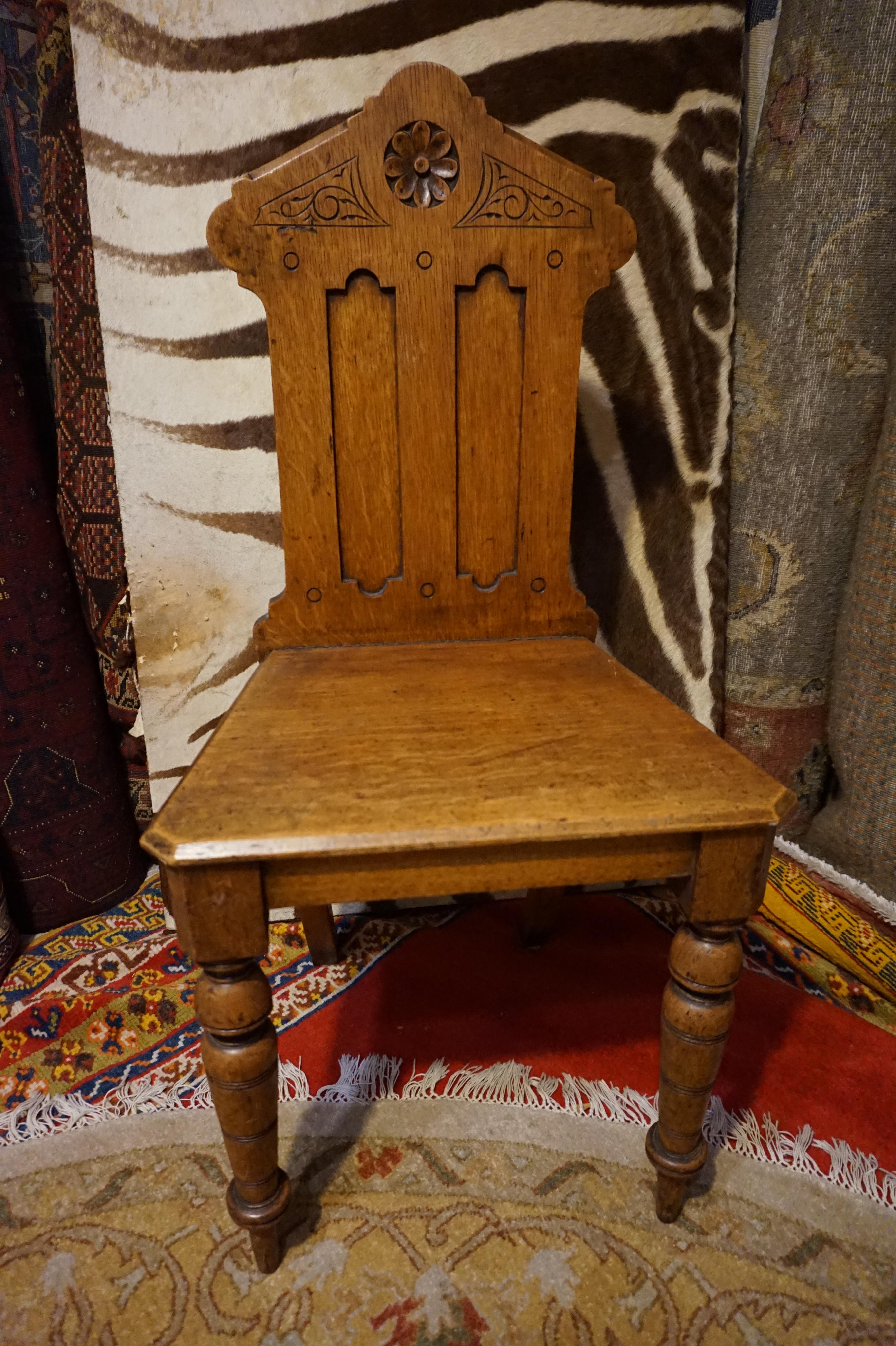 Solid Oak hand carved English Gothic Revival chair in excellent original condition. Sturdy and well proportioned. Skilfully carved with dowel and peg work joinery. Upright posture. Original patina. Exudes character. A singular chair for occasional
