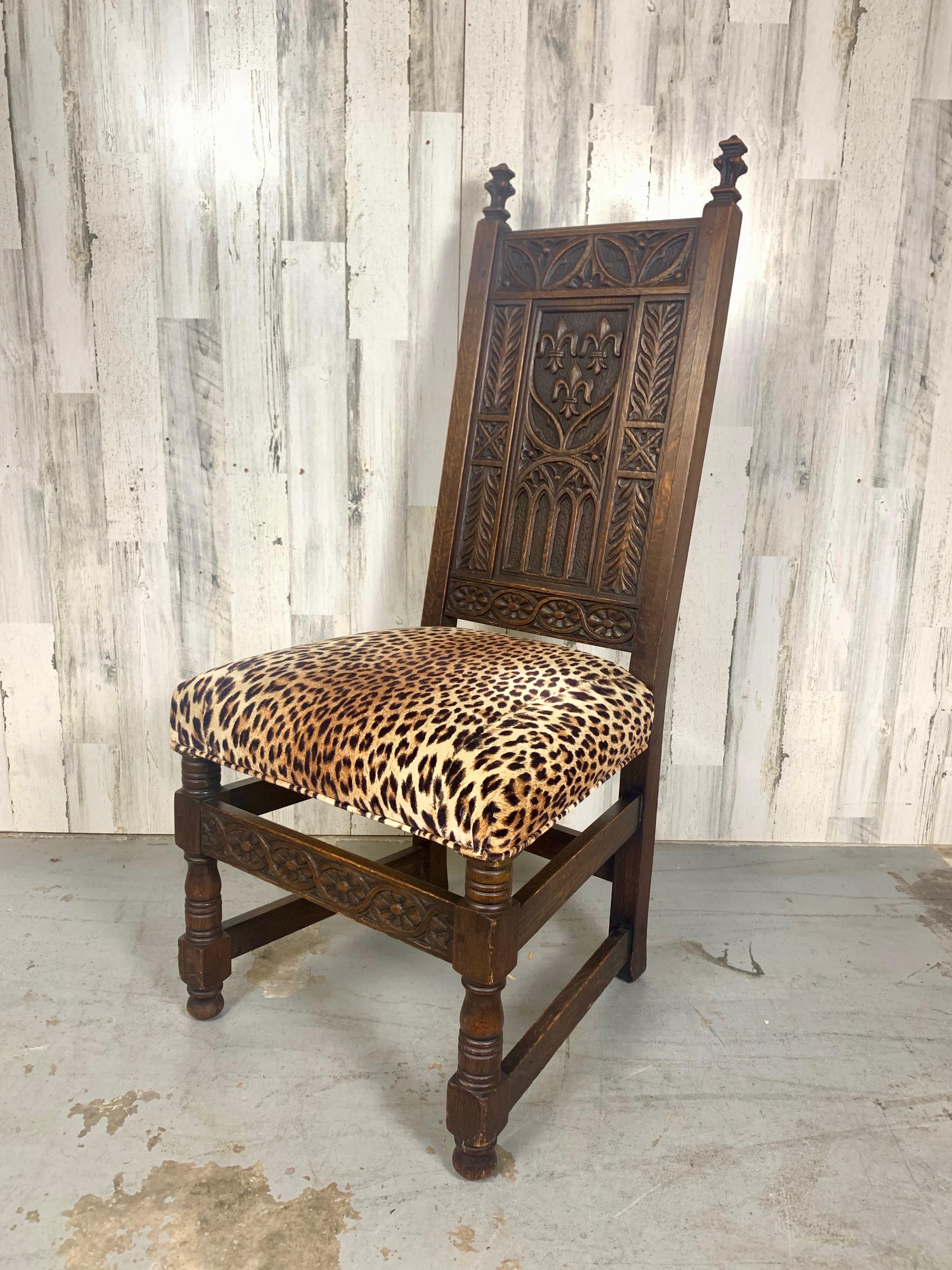 Beautiful hand carved Gothic style hall chair with Fleur-de-lis, Trefoils and other gothic accents. Chair has a good weight to it with the leopard print fabric for fun.