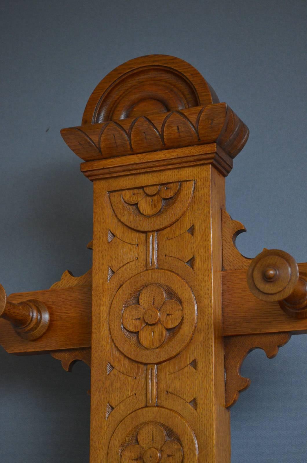 Sn3876, Victorian Gothic Revival oak coat stand, having eight turned coat hooks on carved support, terminating in a base with lift up comportment and brass umbrella holders, all terminating in rectangular base with removable drip tray. This antique