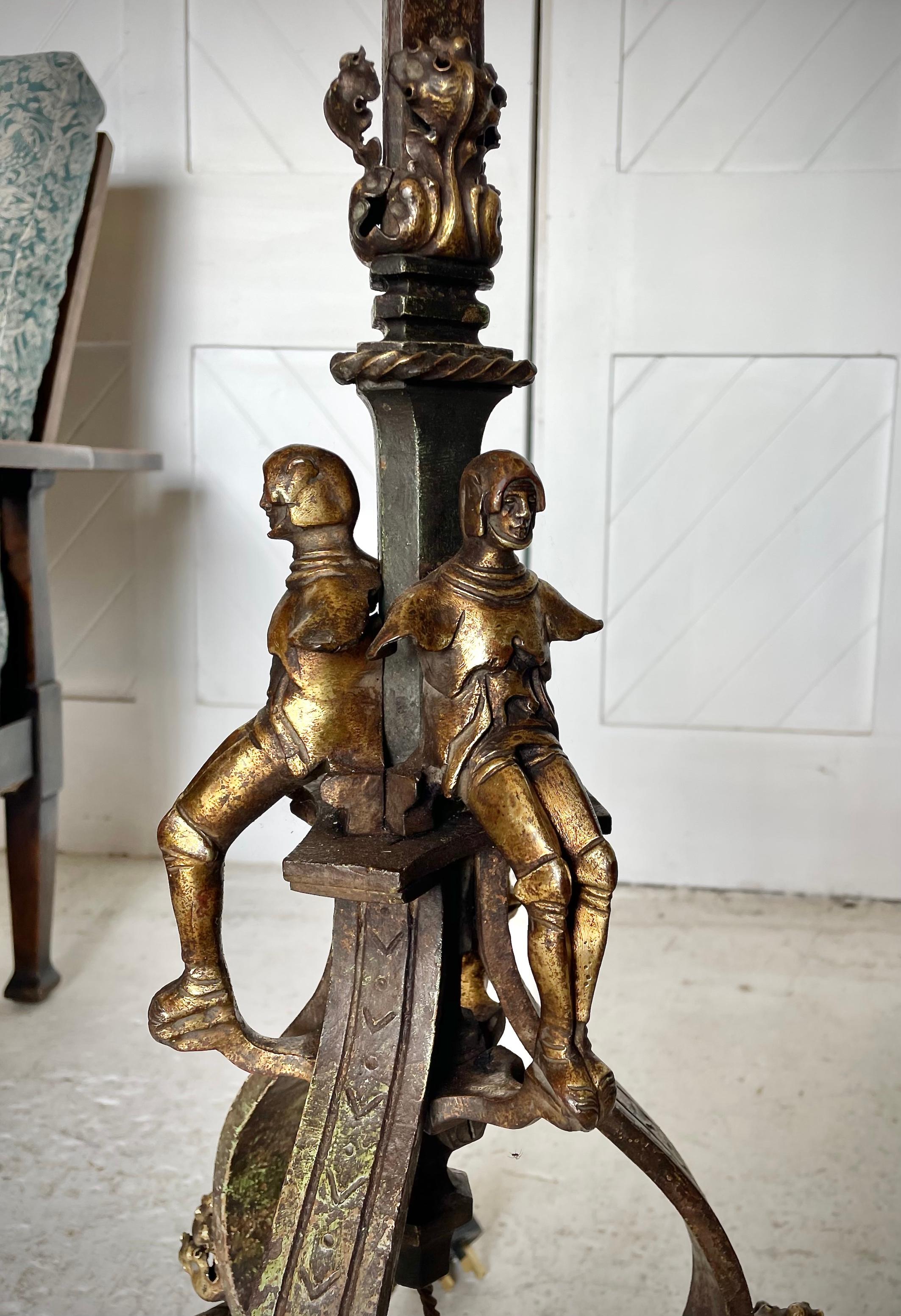 Gothic Revival standard lamp in iron and cast brass 

Depicting medieval masked faces, knights and grotesques

Hand made shade by Tinker & Tallulah for Patch Rogers Design

Circa 1915

Height 196 cm.  Width 42cm.  Depth 39cm 