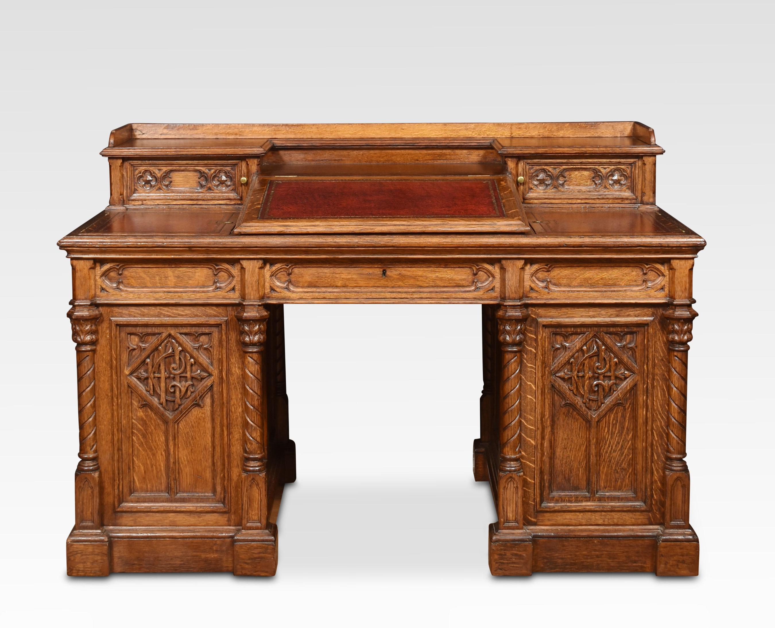 Oak Dickens style desk, the raised gallery, to the central slope front with inset leather writing surface, flanked by two further inset leathers with short drawers above. To the two pedestals with carved gothic panels opening to reveal three
