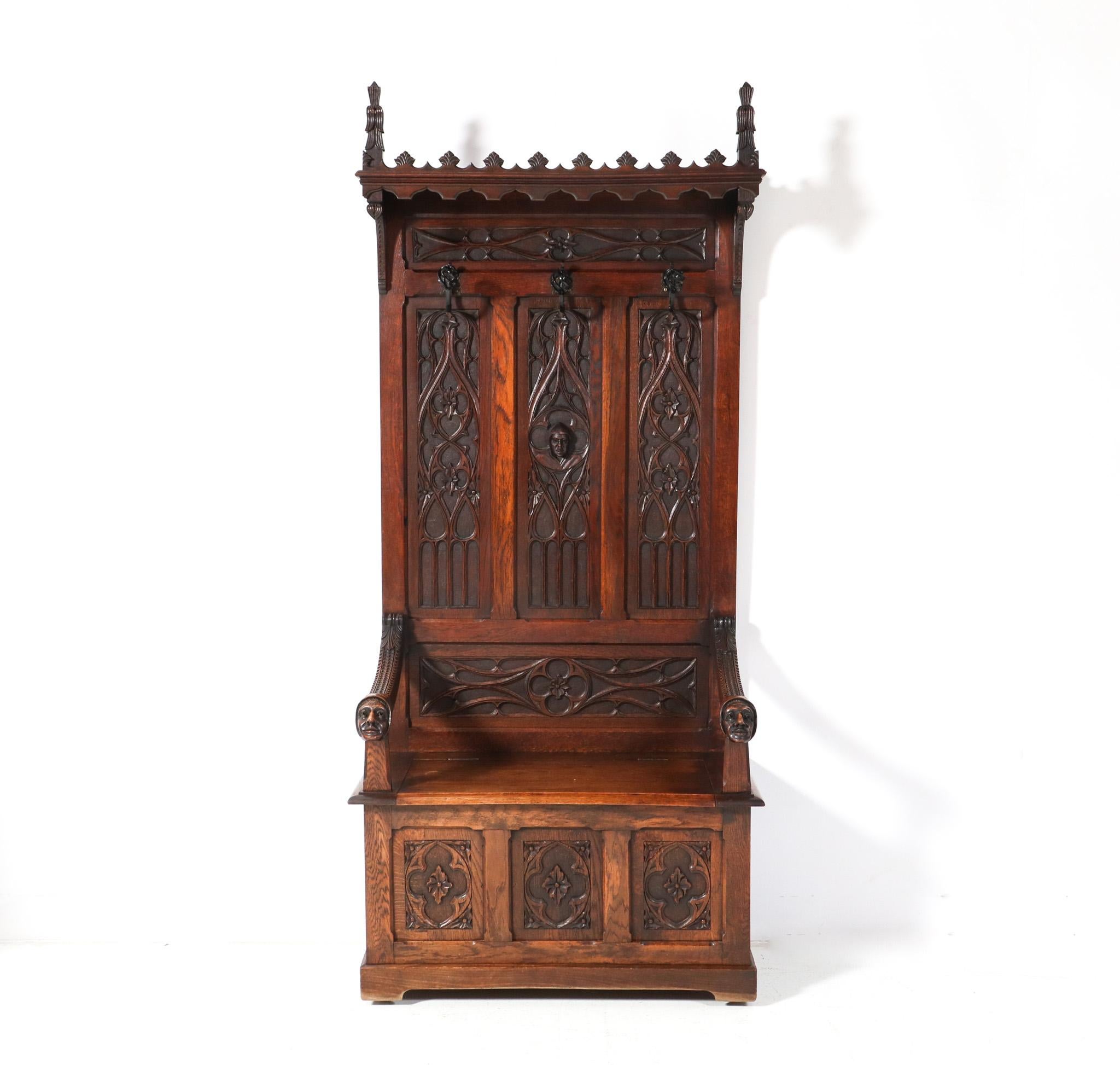 Magnificent and rare Gothic Revival hall bench.
Striking Dutch design from the 1900s.
Solid oak with original hand-carved decorative elements.
Original hand-carved decorative faces at the end of the armrests.
Underneath the seat, there is room for