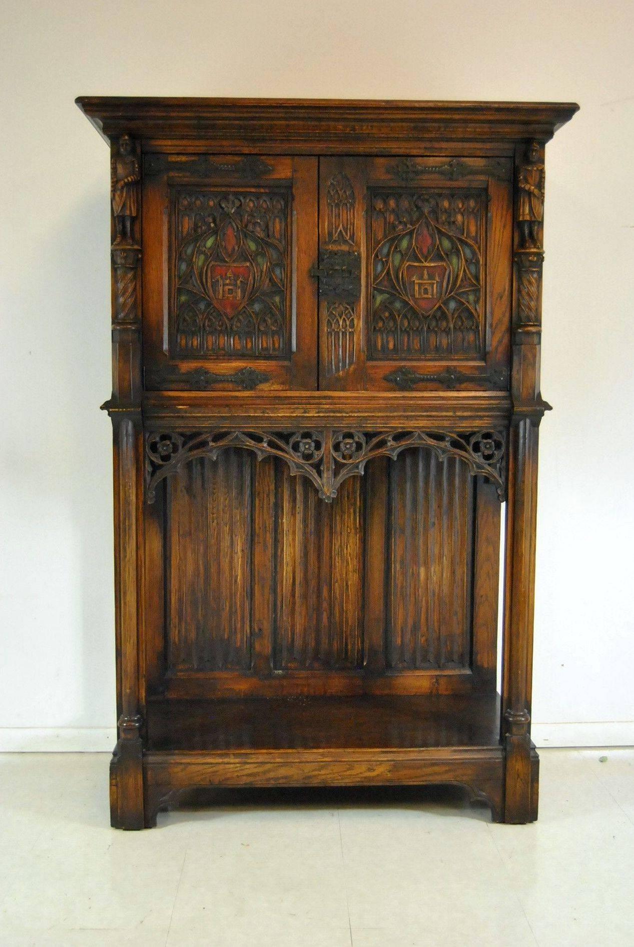 A handsome Gothic Revival oak knights cupboard, server or tall chest. This piece is breath taking with the golden brown patina. The upper section has twin doors featuring centring shields flanked by figural knights on the sides. The knights each