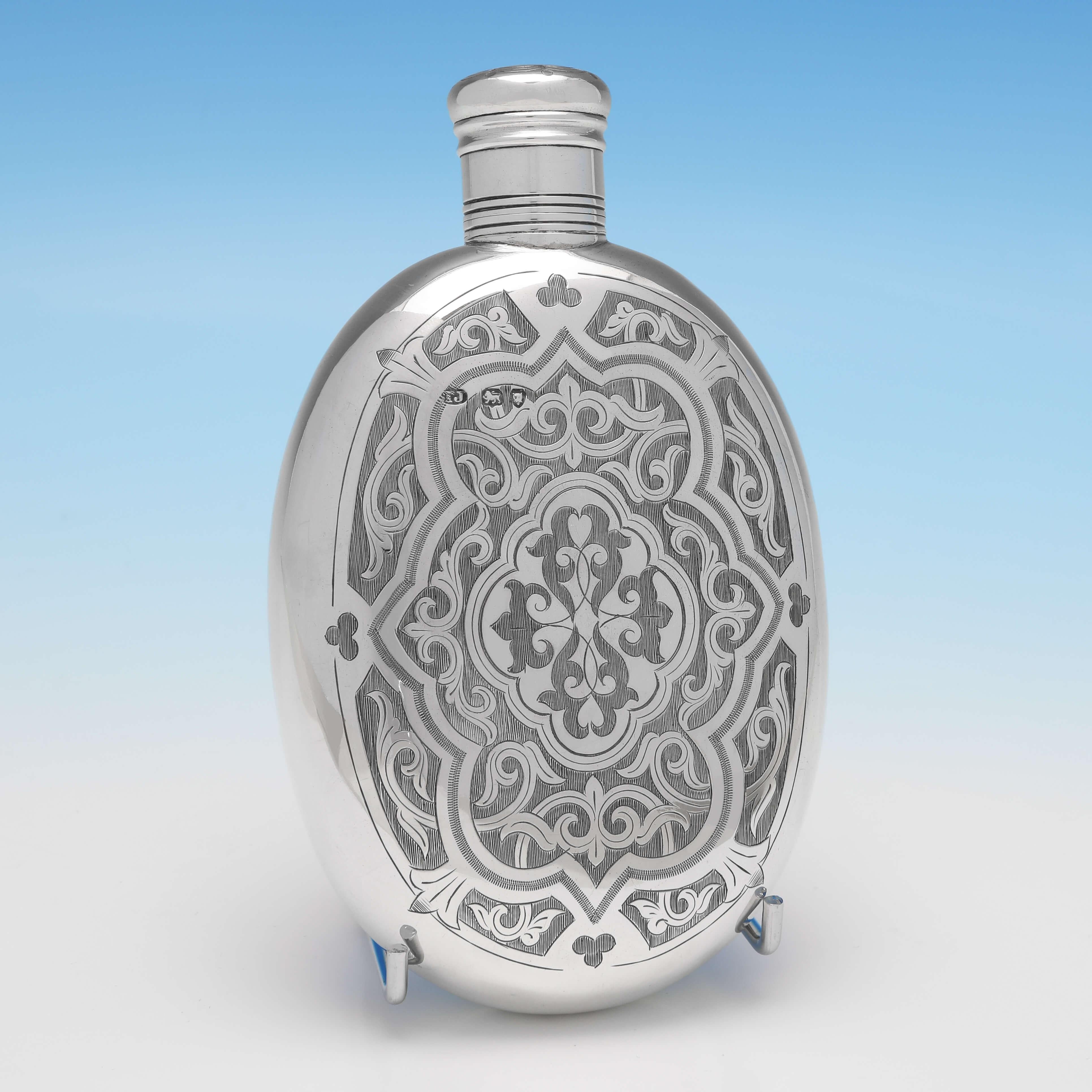 Hallmarked in London in 1875 by Thomas Johnson, this striking, Victorian, antique sterling silver hip flask, is oval in shape, and features wonderful gothic revival engraving, and a removable lid. The hip flask measures 6