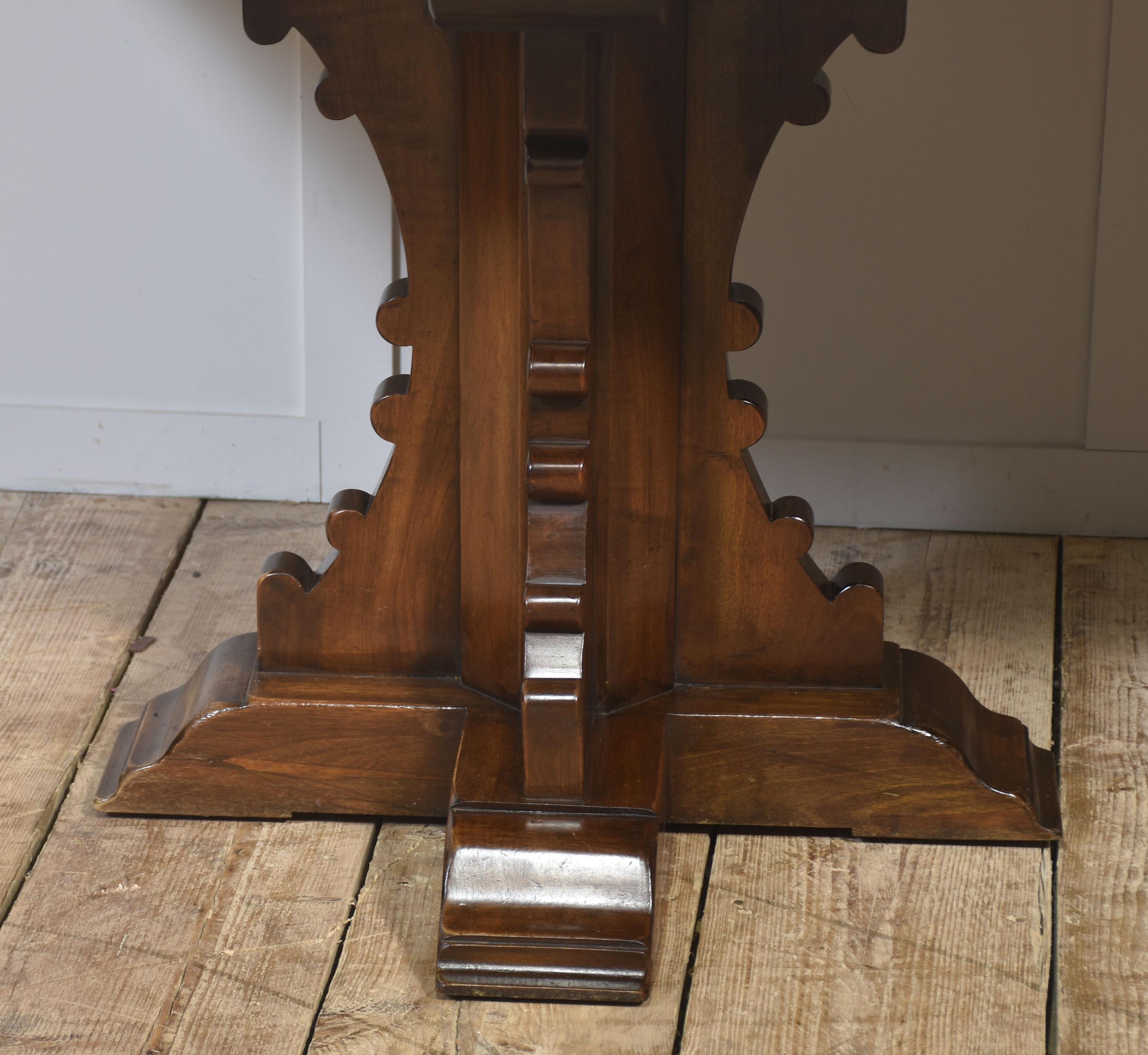 Impressive Gothic Revival refectory dining table. The rectangular top is finished with a subtle carved edge and rests upon twin pedestal bases, each with bold Gothic-inspired silhouettes, shaped cut-outs, and stepped plinths.
This generously