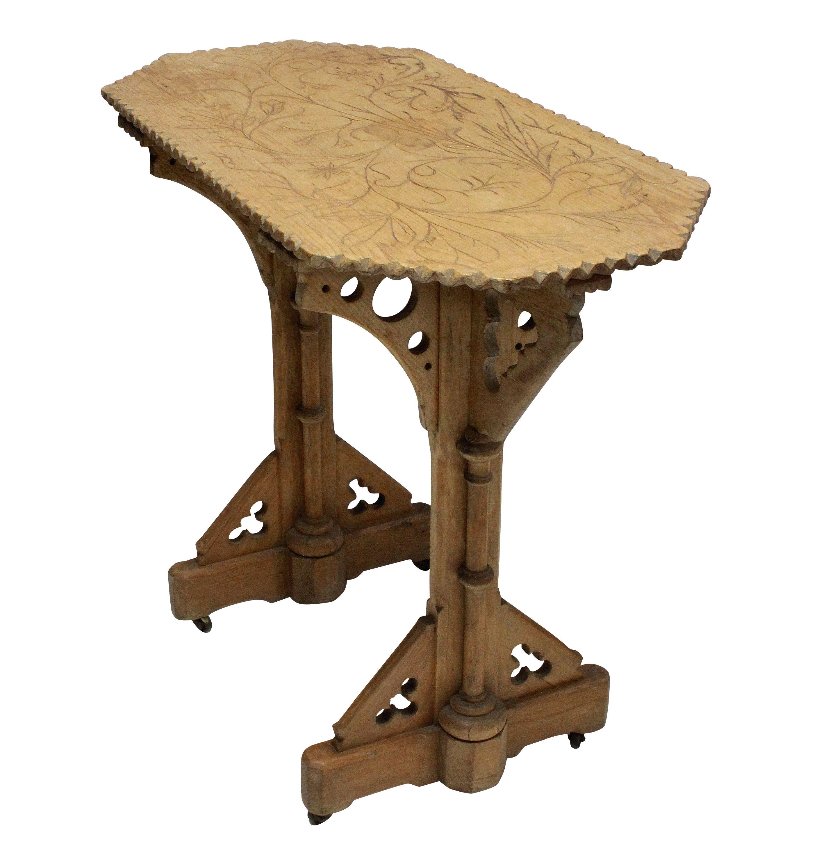 An English Gothic Revival pine side table. Crisply carved throughout, and on small brass casters.
