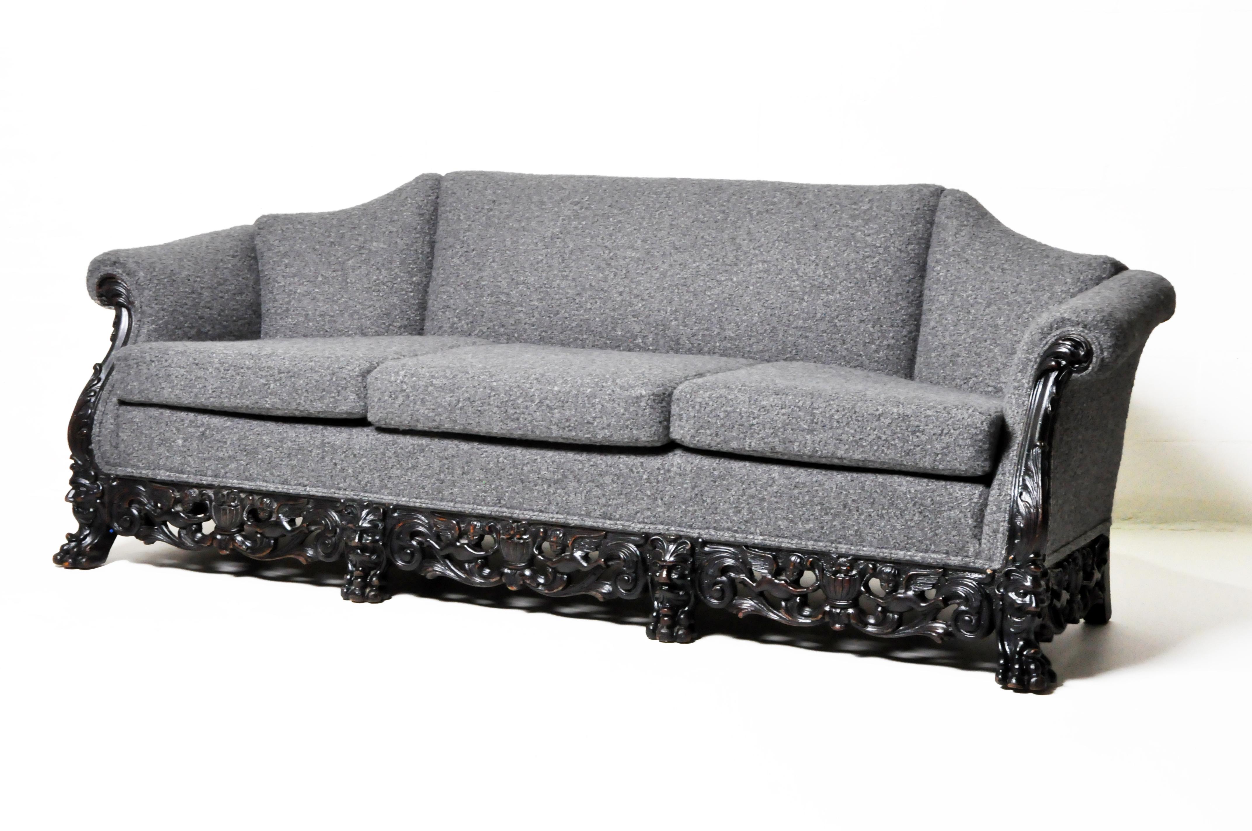 Dieses einzigartige 3-Kissen-Sofa verfügt über einen außergewöhnlichen handgeschnitzten Rahmen aus massiver Eiche mit Klauenfüßen, wirbelnden Ranken und geflügelten Cherubinen. Die weiche Bouclé-Polsterung und die Innenfüllung sind neu, der