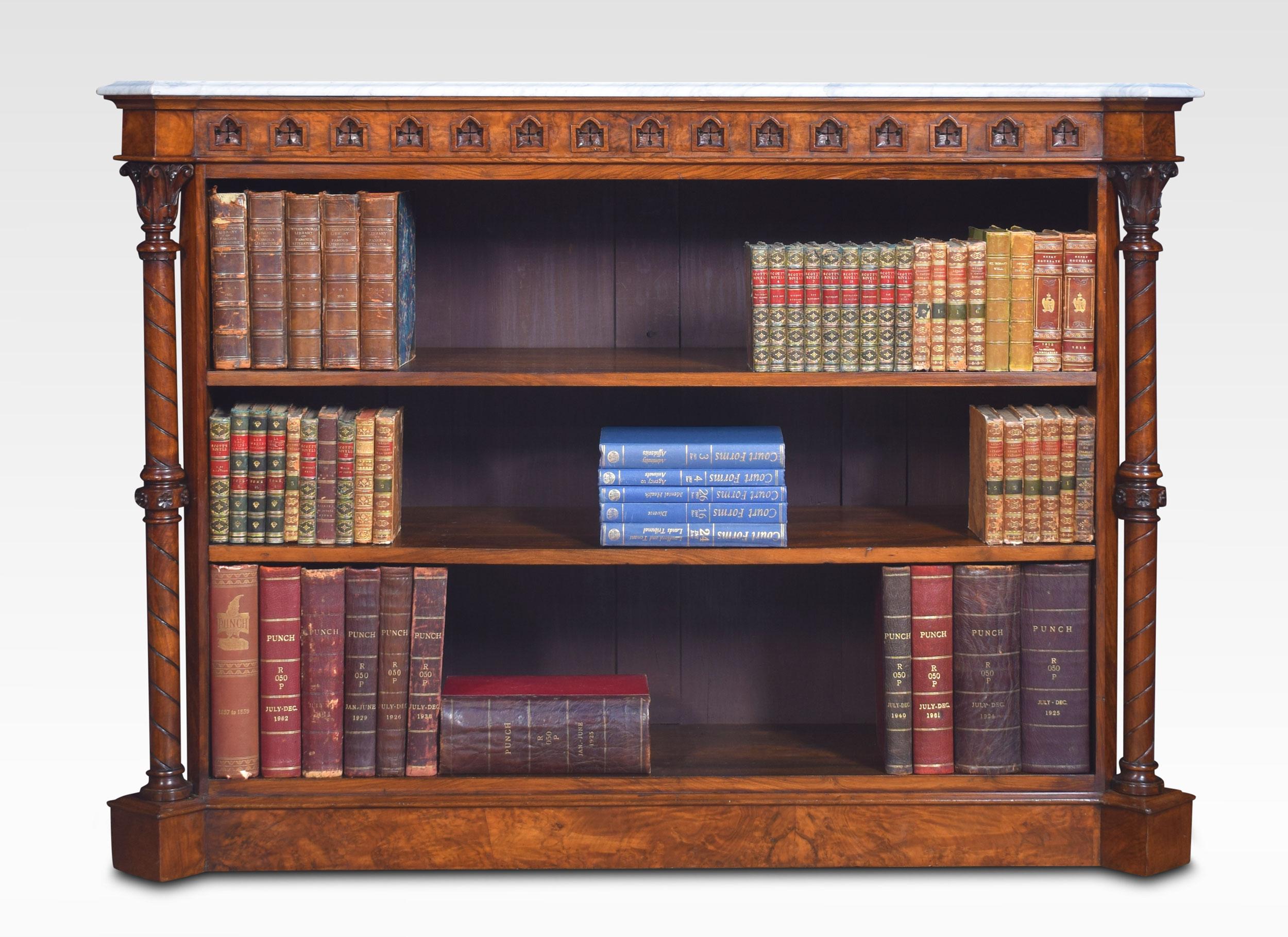 Gothic revival walnut open bookcase, the large rectangular white veined marble top with canted corners above a pierced ecclesiastical frieze. Supported on circular columns with carved capitals, enclosing two adjustable shelves. All raised up on
