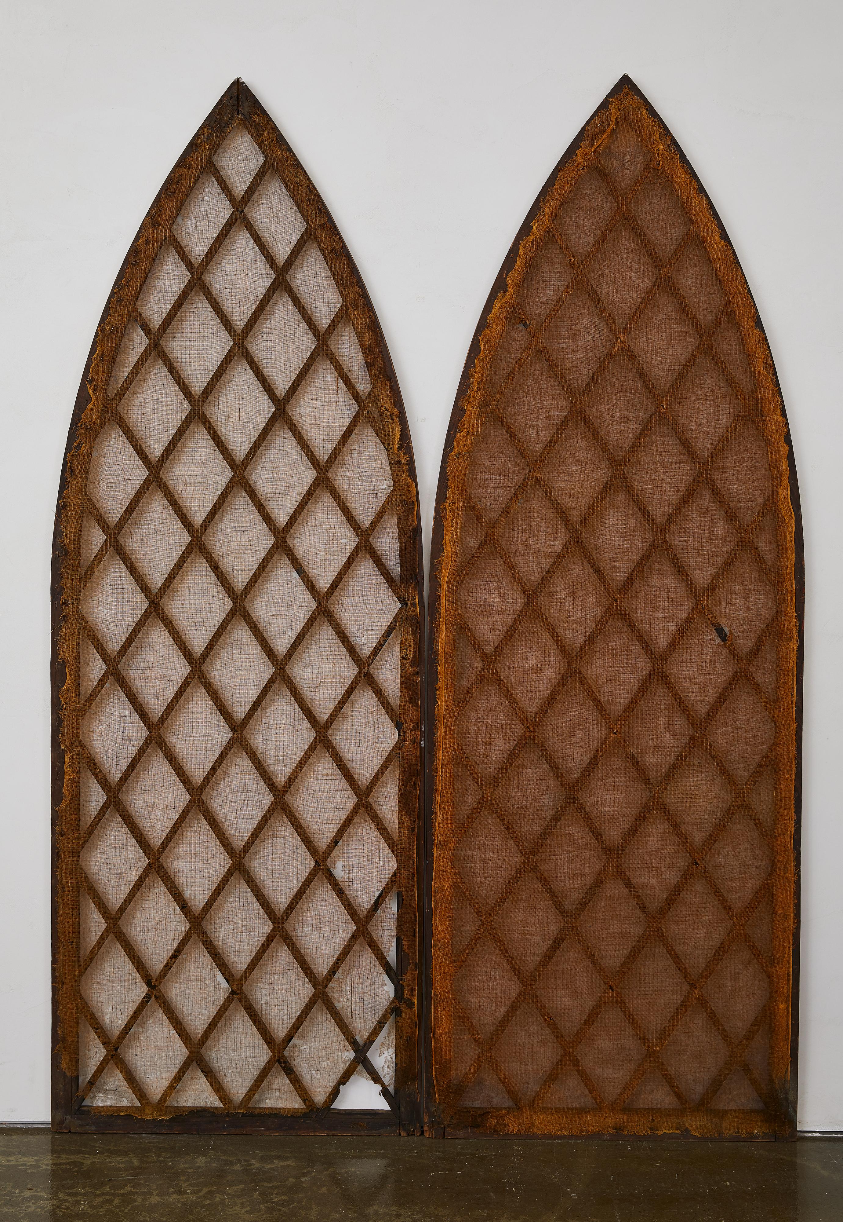 A stunning pair of antique Gothic lancet-arched church window screens featuring intricate lattice detailing, handcrafted woodwork, and a richly aged patina. These architectural elements likely originated from a 19th- century church or cathedral and
