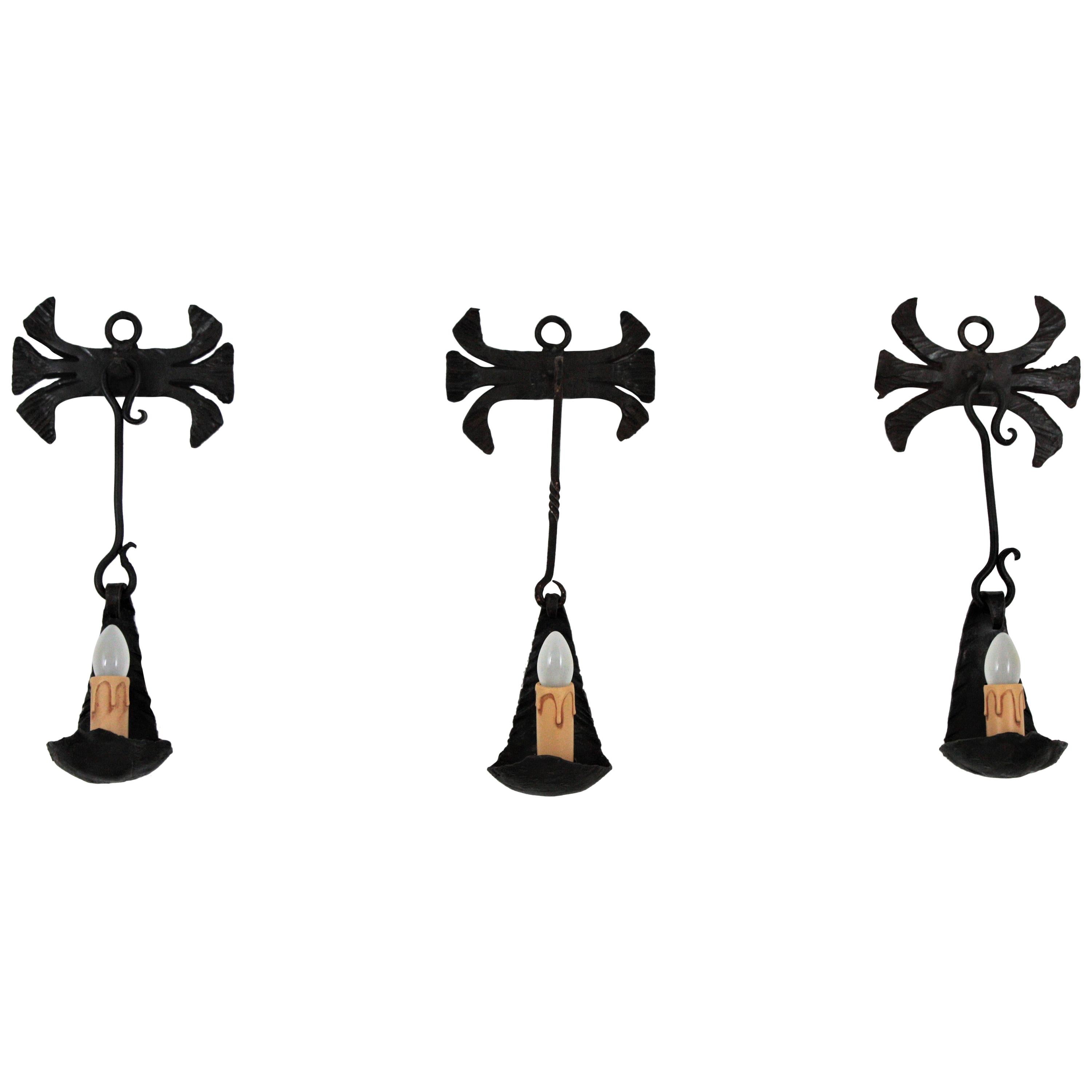 Set of three Gothic style candleholder oil lamps converted into wall sconces, Spain, 1930s-1940s.
Each of these three wall lights were all made by hand in wrought iron. Created to be wall oil lamps or wall candleholders. We have converted them to