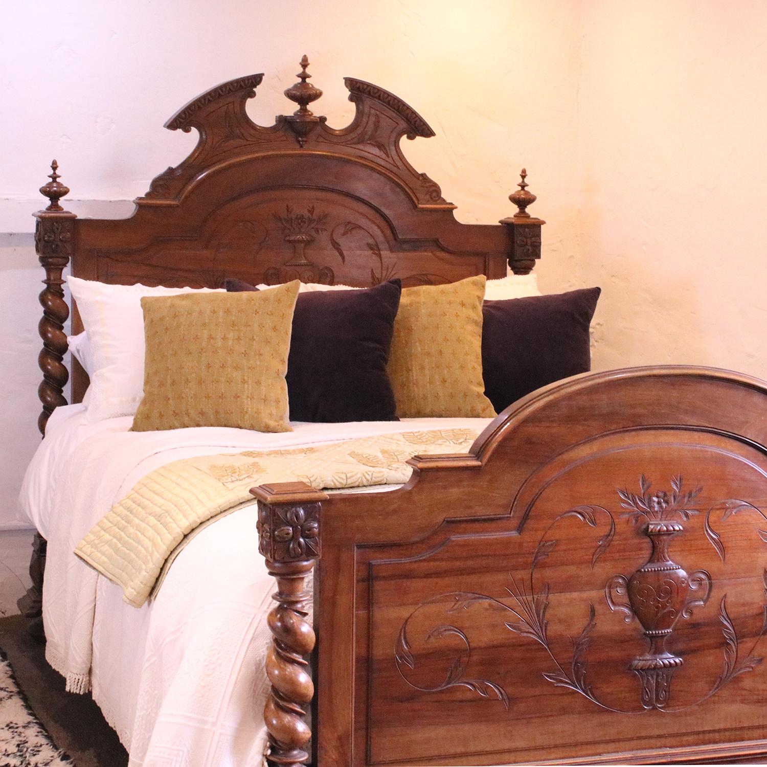 A gothic style bedstead in walnut with decoratively carved head panel, ornate pediment and finials, and turned barley twist posts.

This bed accepts a British king size or American queen size, 5ft wide (60 inches or 150cm) base and mattress