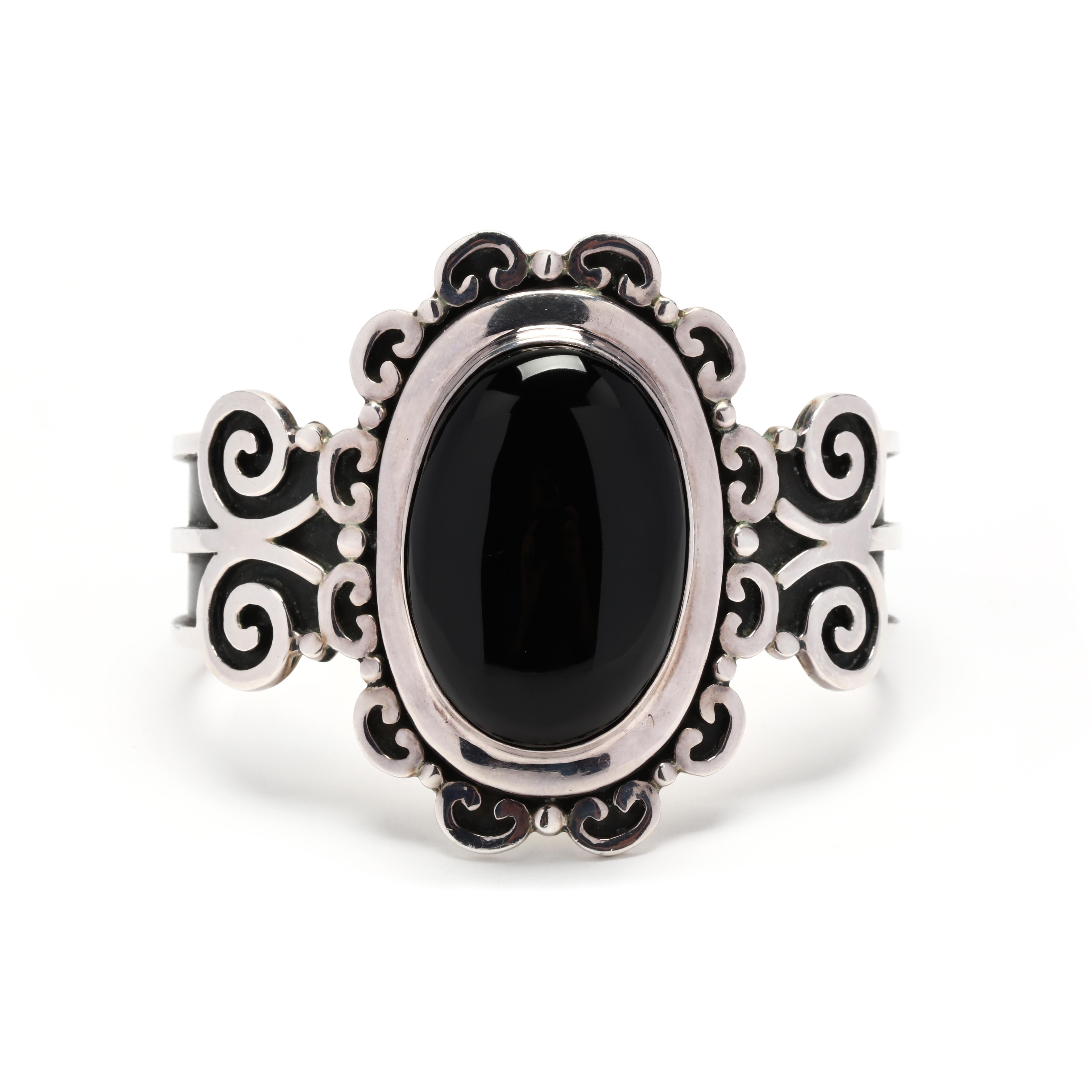 A vintage sterling silver gothic style black onyx cuff bracelet.  This adjustable bracelet features a center oval cabochon black onyx, surrounded by scrollwork frame, with oxidized accents.  It is stamped 925 Mexico. 

Stones:
-Black Onyx, 1
-oval