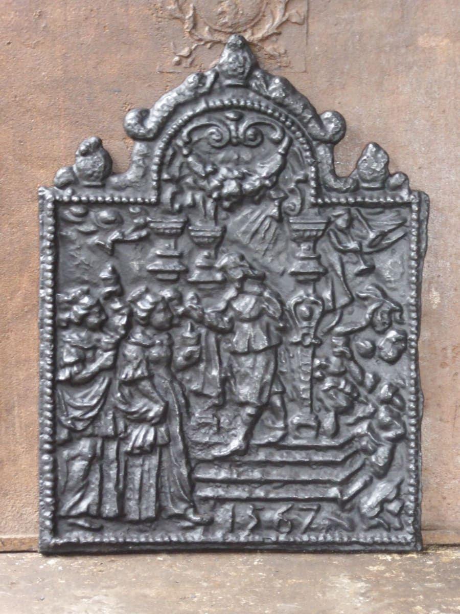 Gothic Style German fireback depicting a religious theme. The fireback is made of cast iron and has a black / pewter color. The fireback is in a good condition and does not have cracks.