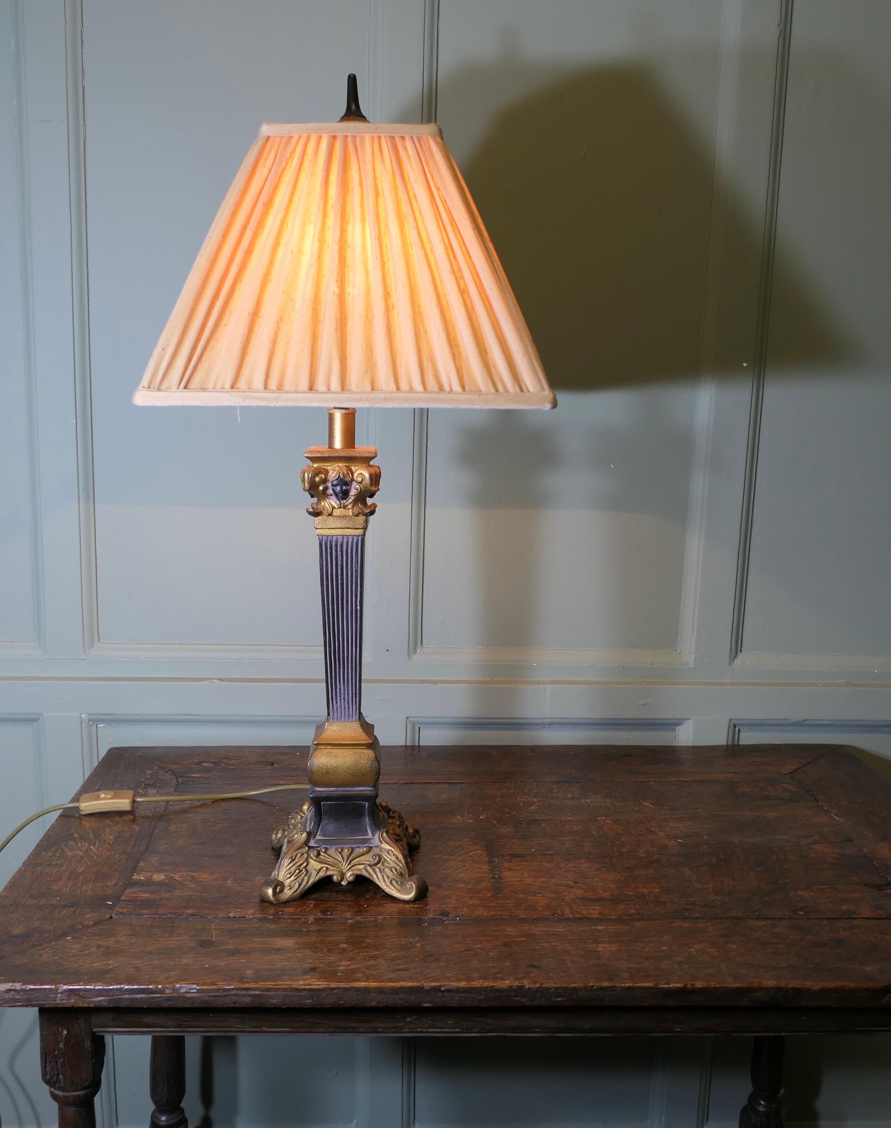 Lampe de table de style gothique 

La lampe repose sur un pied carré en bronze. Elle possède une colonne centrale à quatre faces qui présente un visage de chaque côté.

Il s'agit d'une lampe inhabituelle avec un abat-jour carré et plissé. 
La lampe