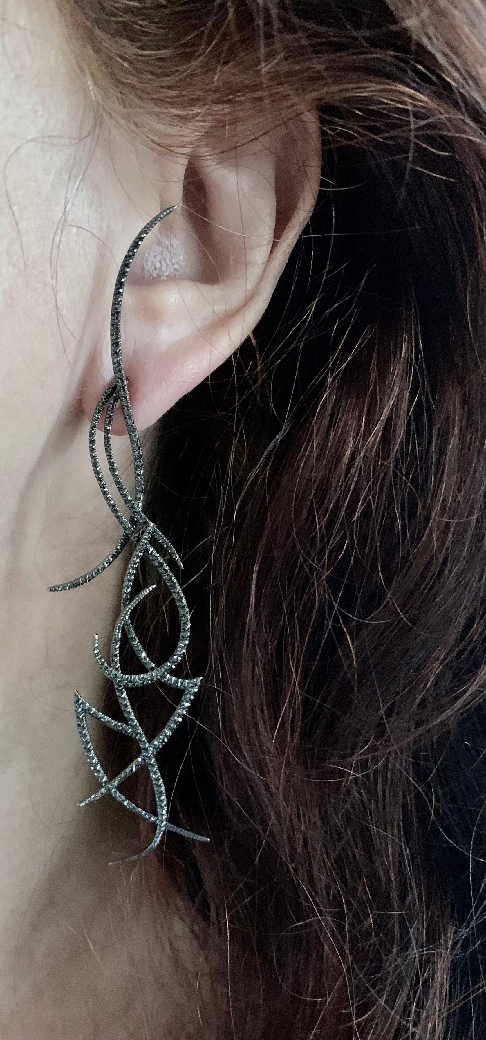 Stunning and dramatic 5.75 inch long articulated full cut black diamond earrings. The diamonds totaling approximately 3.3 carats are reverse set with the cullet pointing forward. 
Designed as a series of fine interconnected scrolls and linear artful