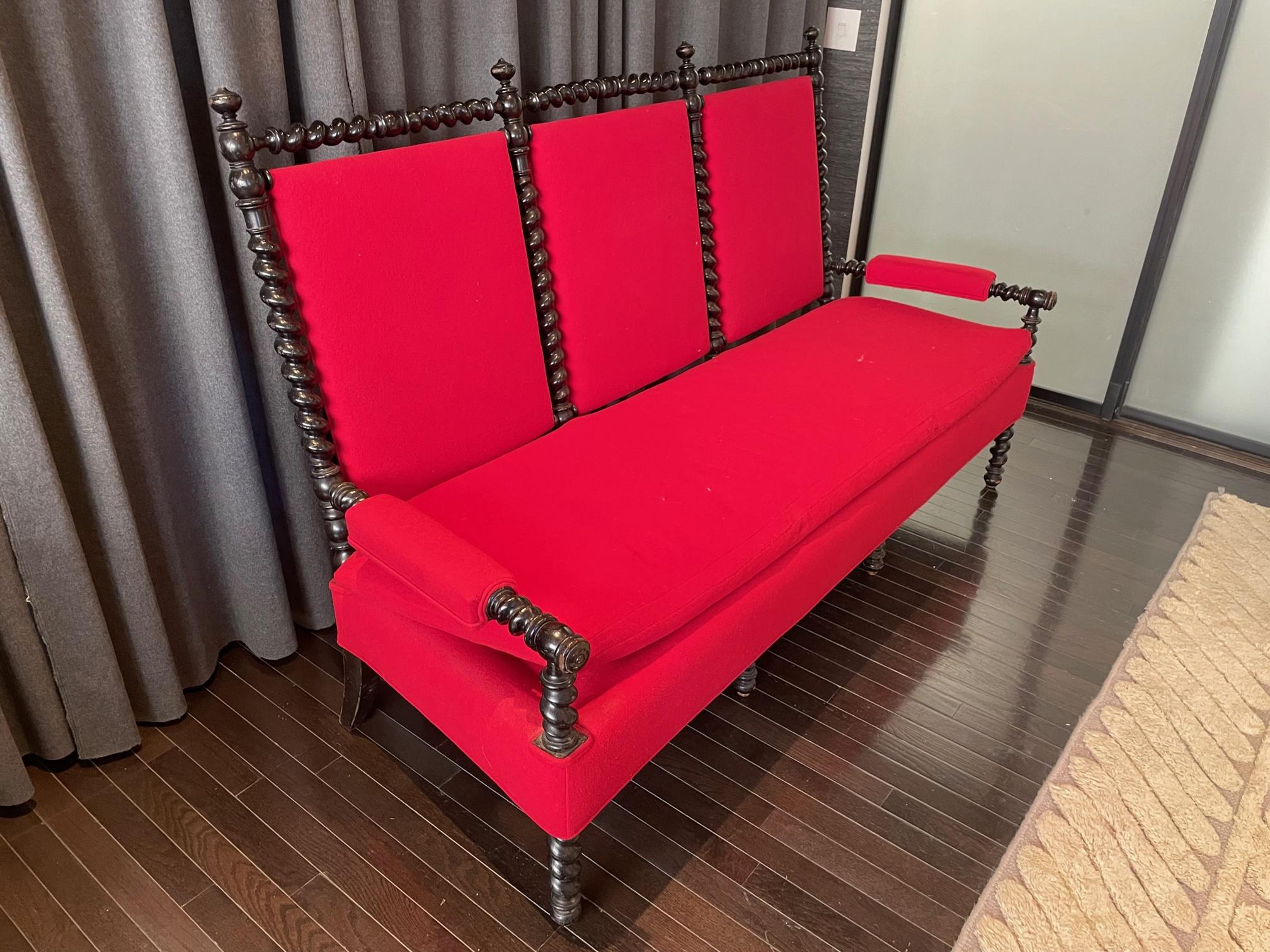 Gilded Age American settee with upholstered seat and carved mahogany frame with spindle detailing. Seat is reupholstered in a bold red wool blend fabric. Circa 1890-1910.