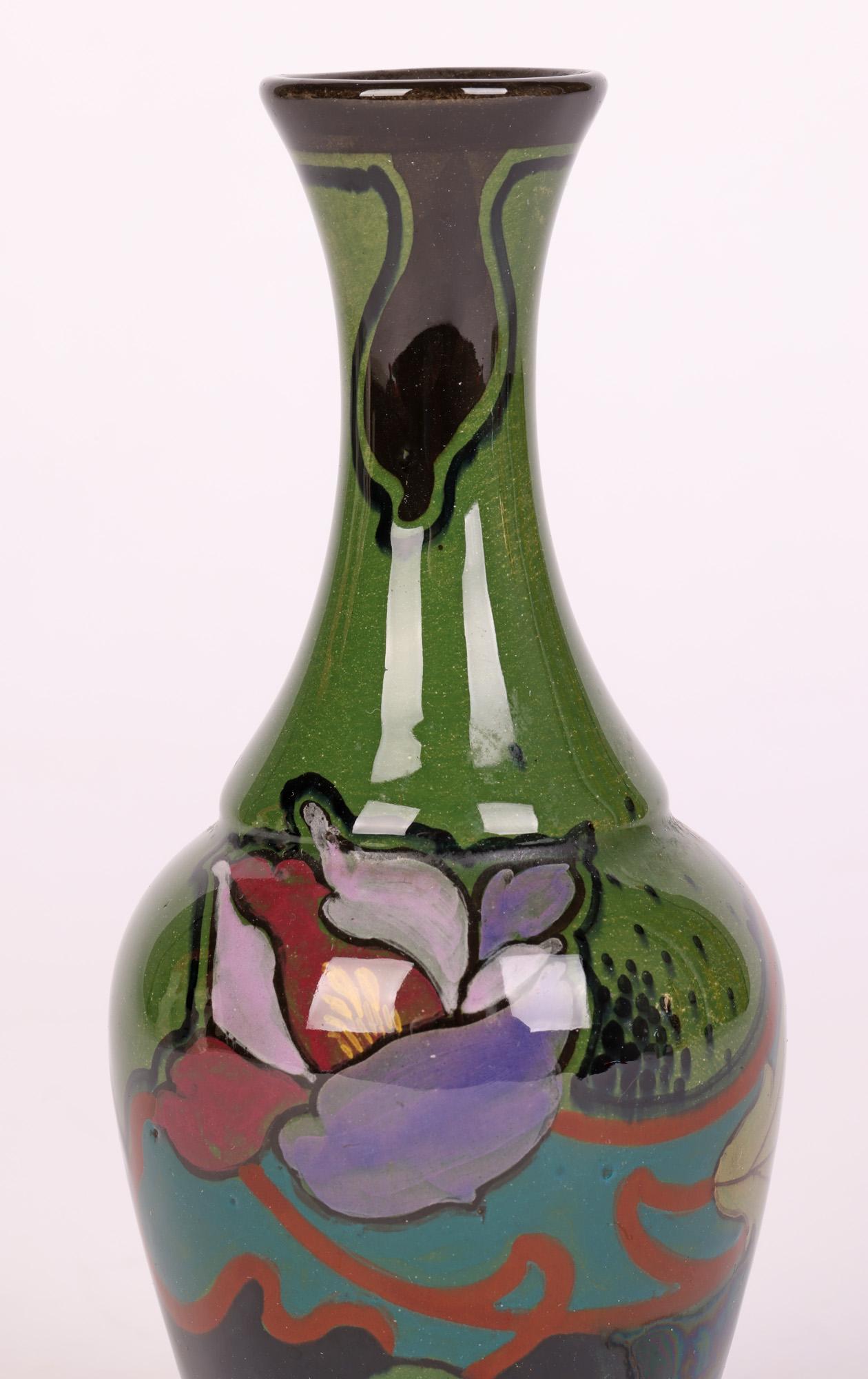 Un élégant vase en poterie d'art hollandaise peint à la main et décoré de motifs floraux stylisés par Gouda Schoonhoven et datant d'environ 1920. Le vase en forme de bouteille, bien empoté, est de petite taille et repose sur un pied étroit et rond,