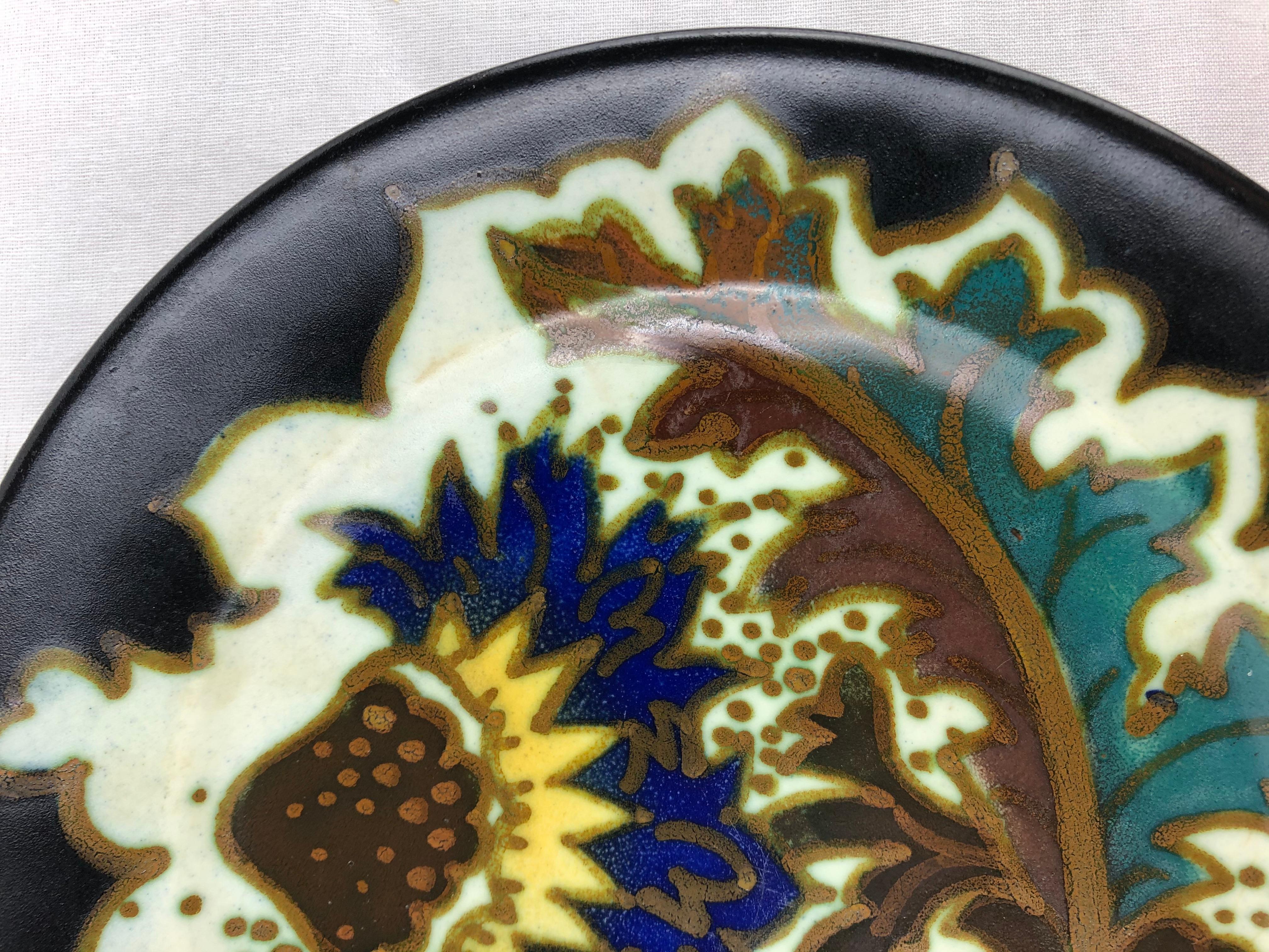 Plat hollandais en céramique Art déco de Gouda, Pays-Bas, avec des motifs floraux et curvilignes traditionnels de l'époque, vers les années 1920, glaçure mate, qui pour nous est le mélange de motifs abstraits et floraux.

Très coloré et agréable à