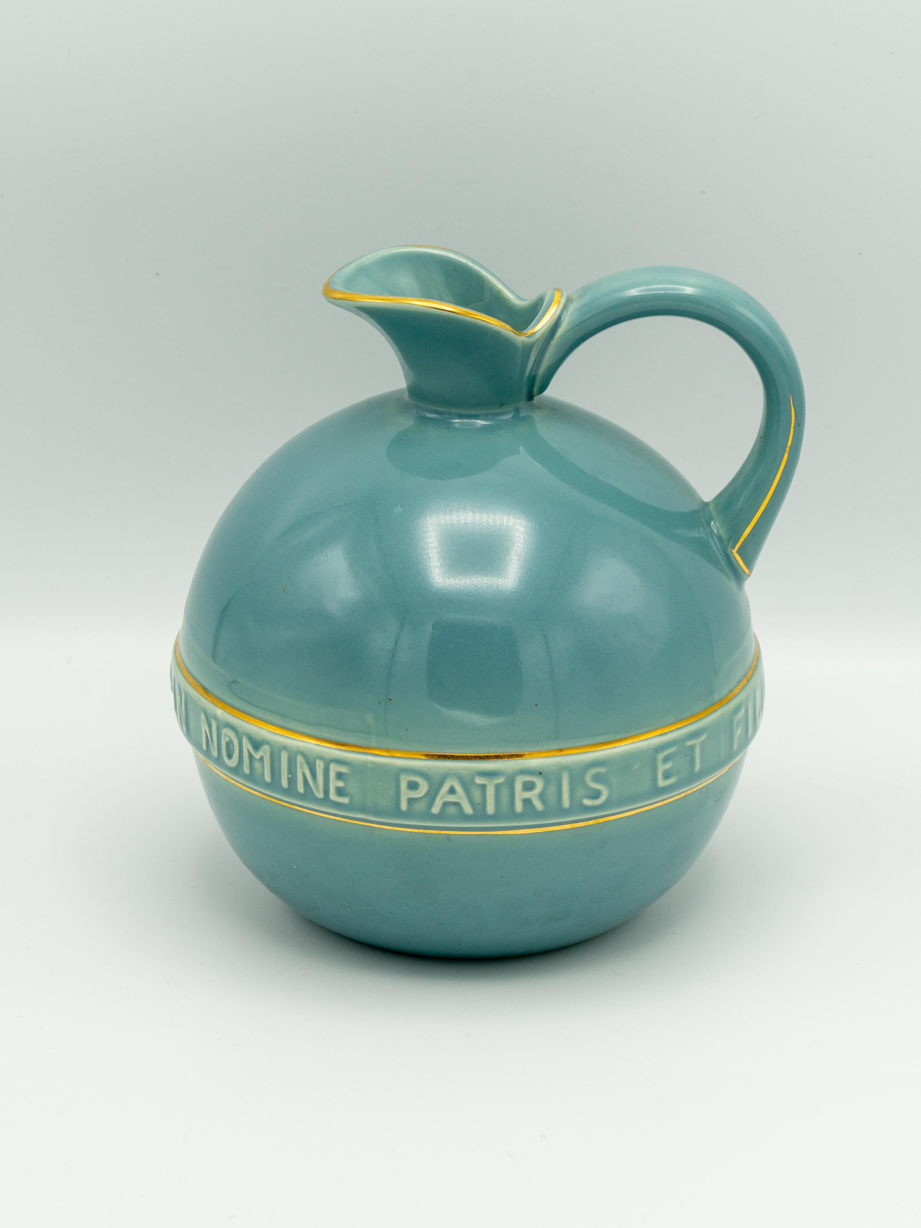 Esta rara jarra de vino de comunión de cerámica, fabricada en la década de 1950 por la alfarería Gouda Plateelbakkerij Zuid-Holland, refleja la elegante sencillez del diseño de mediados de siglo con un profundo propósito espiritual. Diseñada por